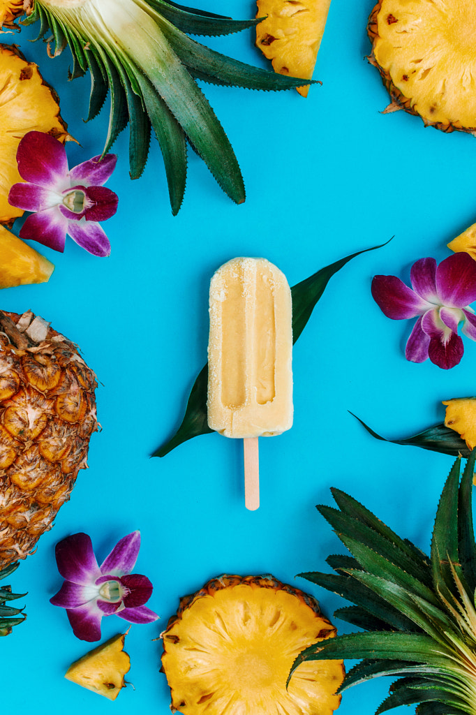 Tropical flatlay with vegan popsicle with various fruits and flowers around on blue by Nataly Lavrenkova on 500px.com