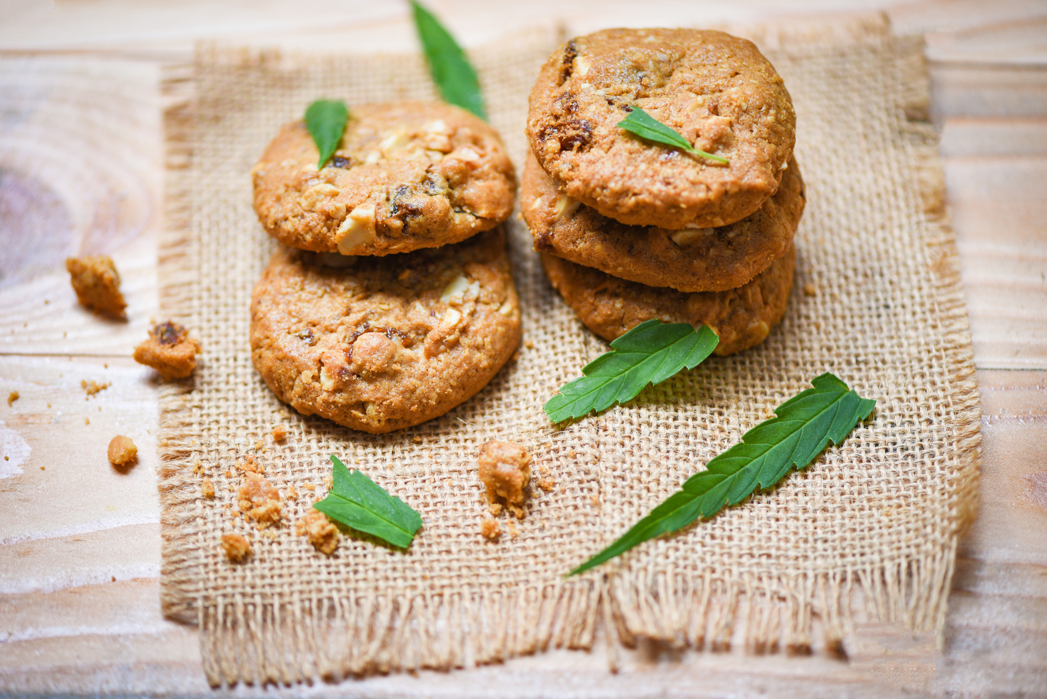 Cookies with cannabis leaf marijuana herb on sack wooden backgro