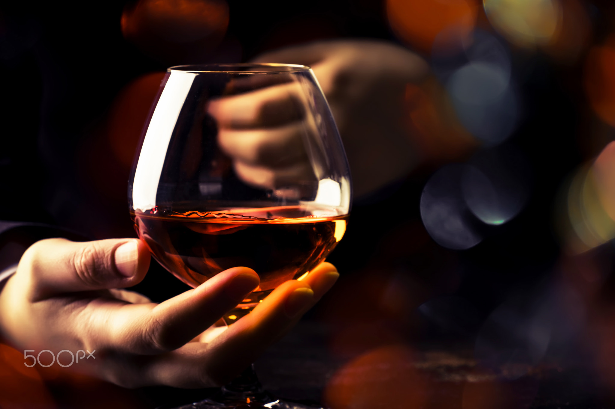 French glowing cognac glass in hand on the dark bar counter back