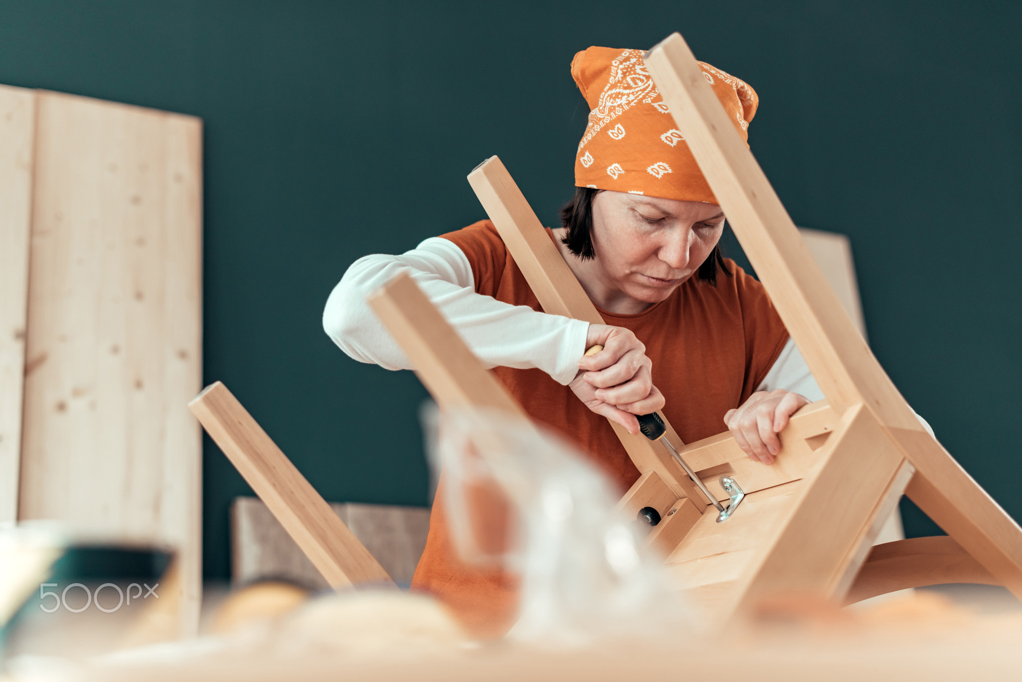 Female carpenter repairing wooden chair seat in workshop