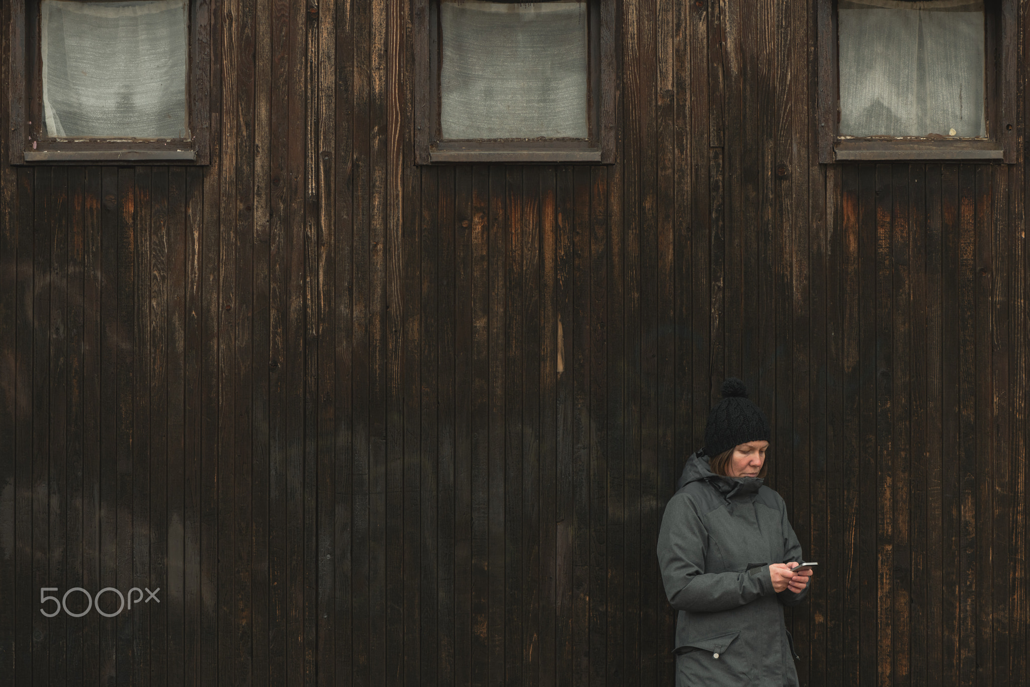 Casual female is texting message on mobile phone on street