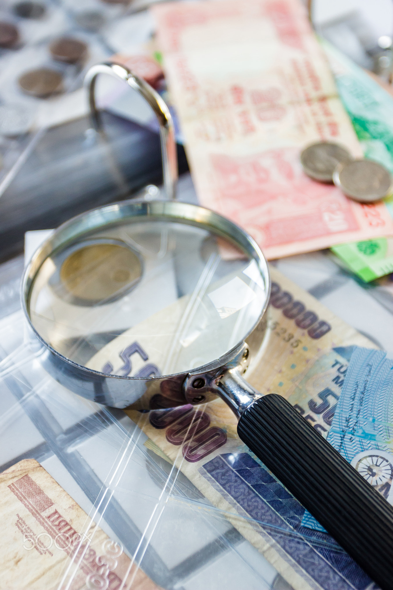 Different old collector's coins with a magnifying glass, blurred background