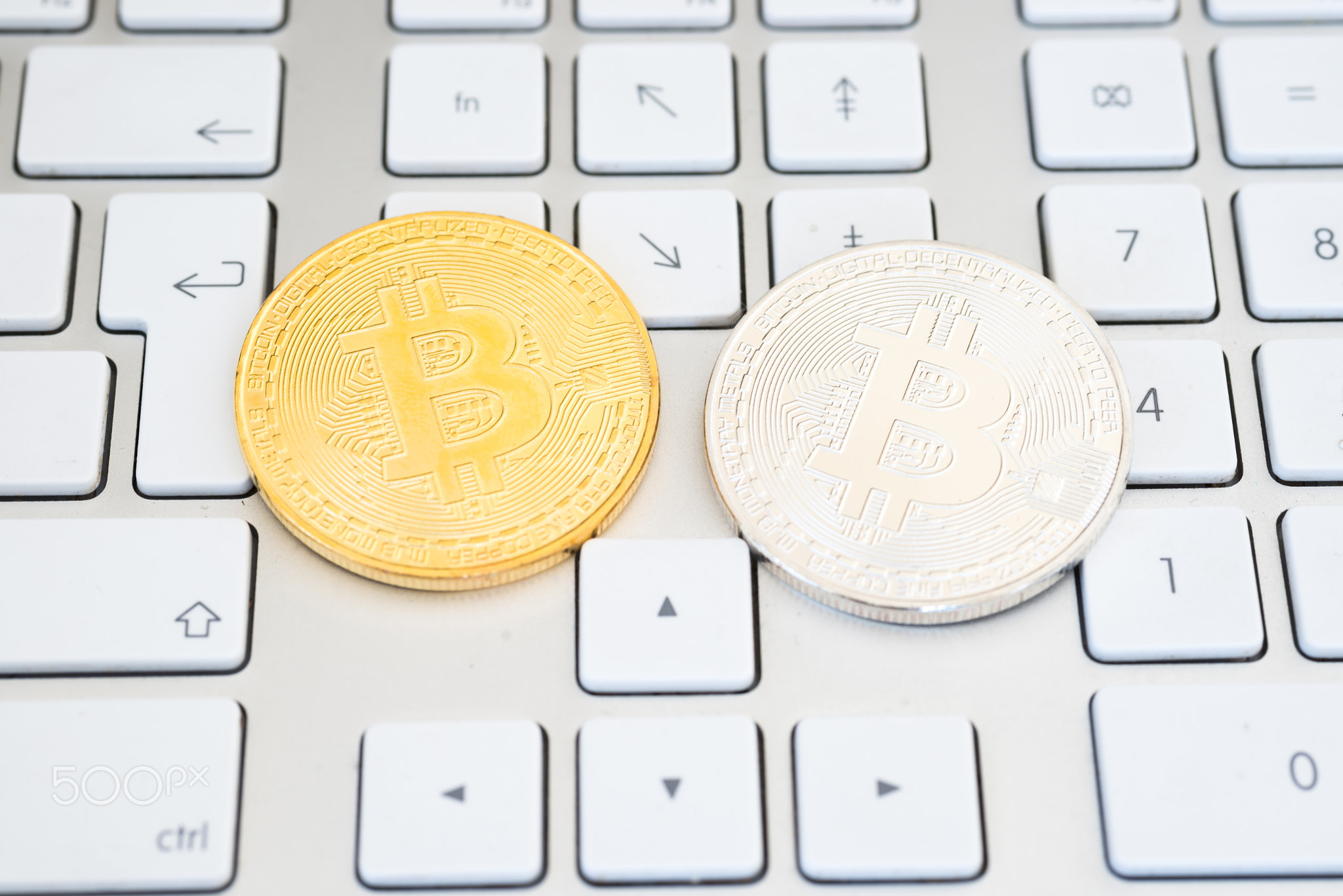 Golden and silver bitcoins on a keyboard