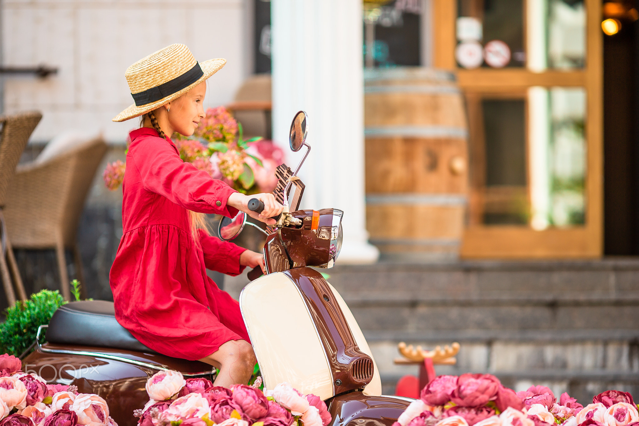 Adorable little girl in hat on the moped outdoors