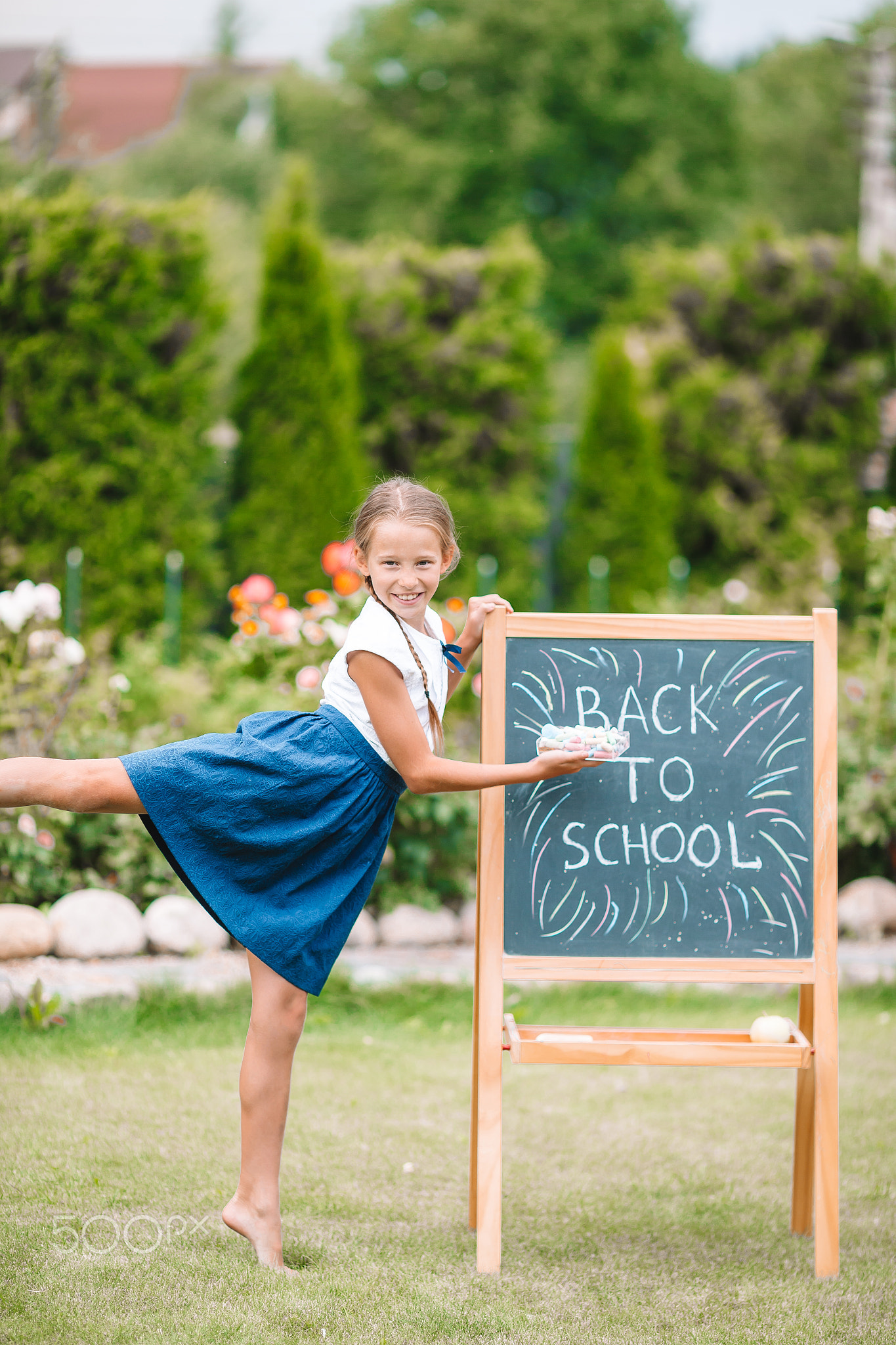 Happy little schoolgirl with a chalkboard outdoor