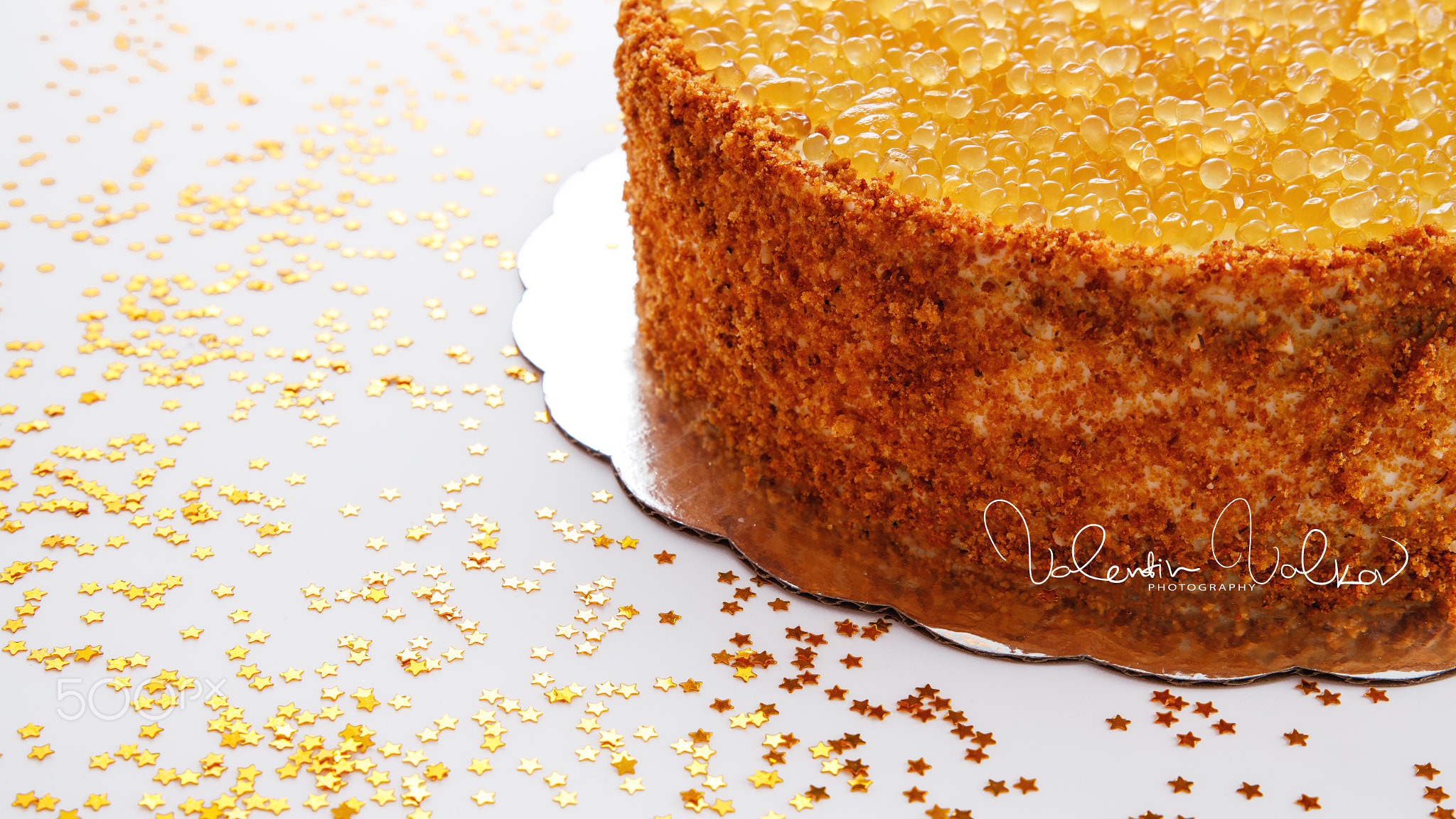 Honey cake with golden pearls, nuts and milk cream isolated on w