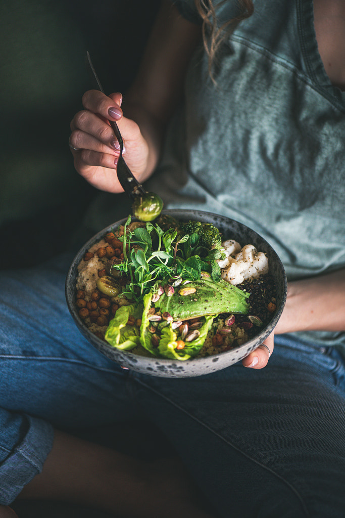 Woman sitting and eating healthy vegan dish from bowl by Anna Ivanova on 500px.com