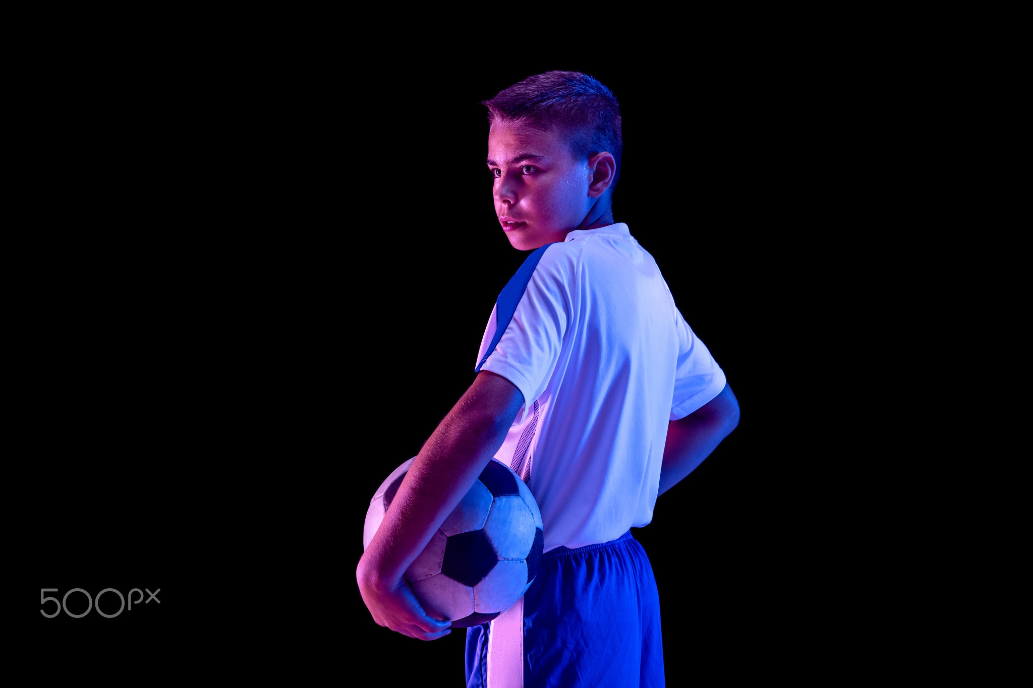 Young boy as a soccer or football player on dark studio background