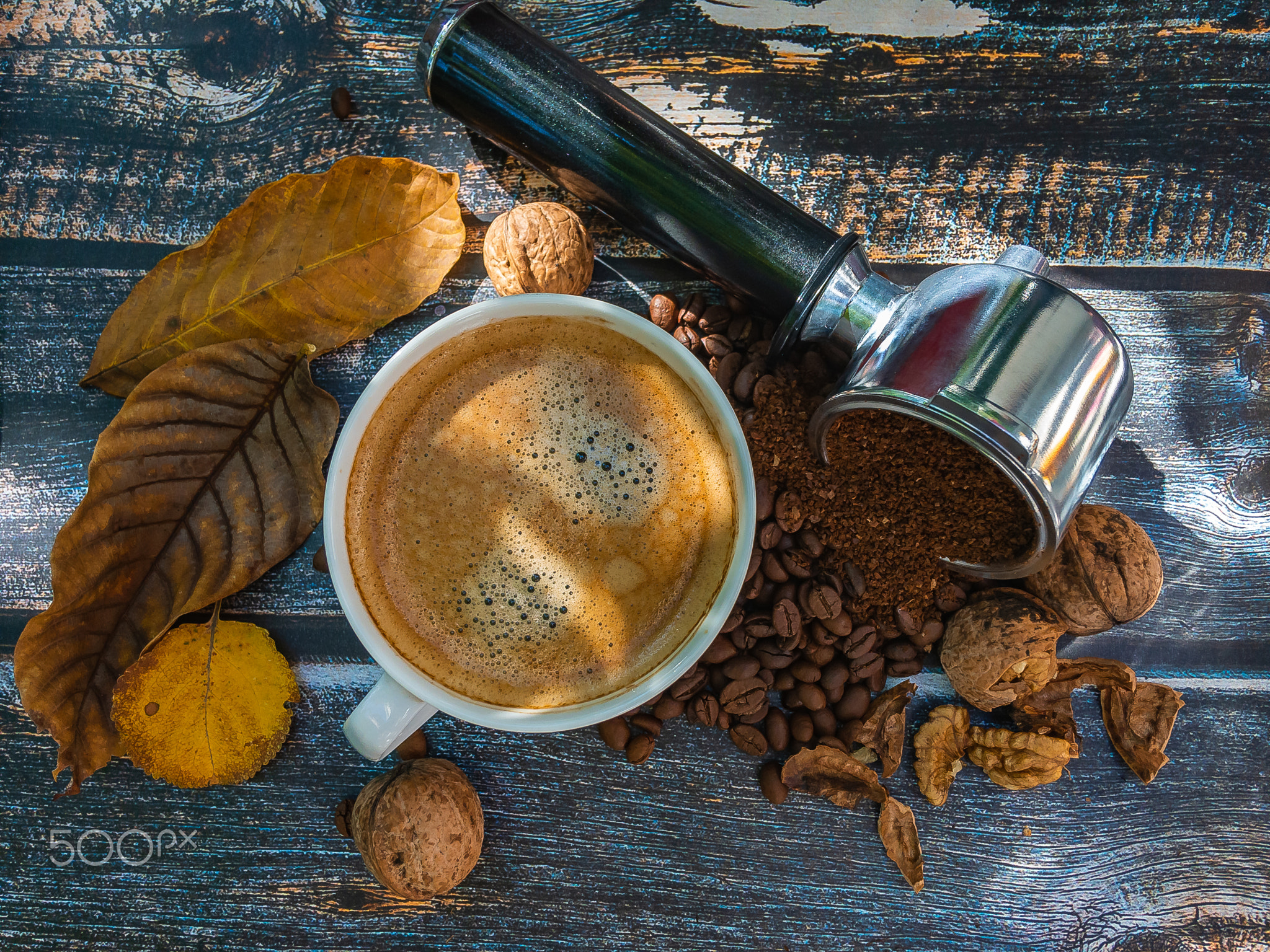 A white cup of espresso surrounded by coffee beans