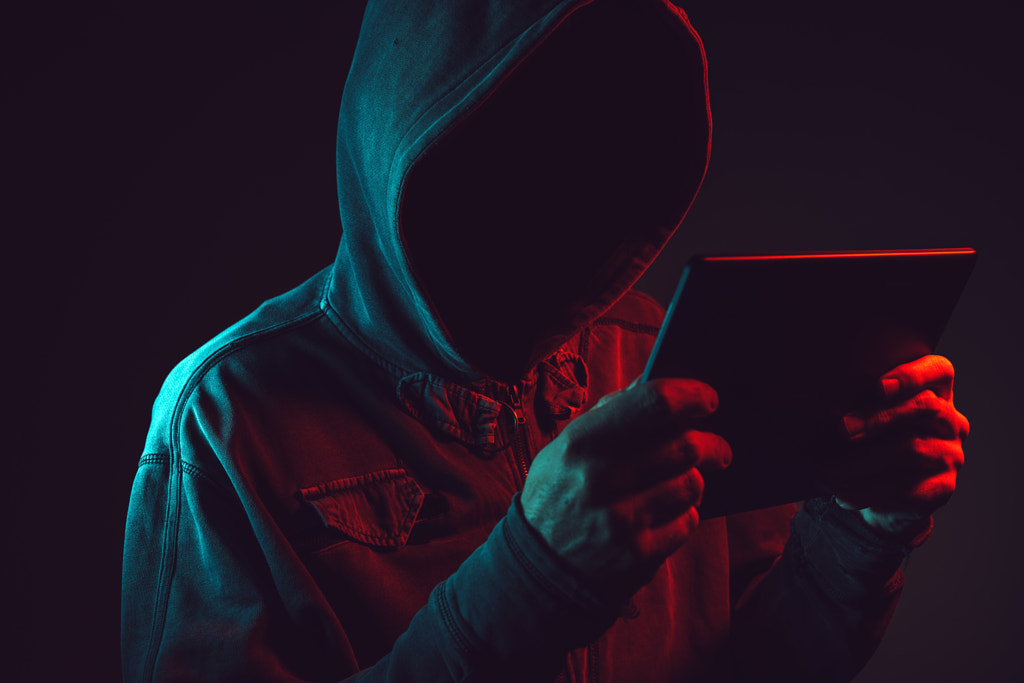 Hooded computer hacker with tablet computer by Igor Stevanovic on 500px.com