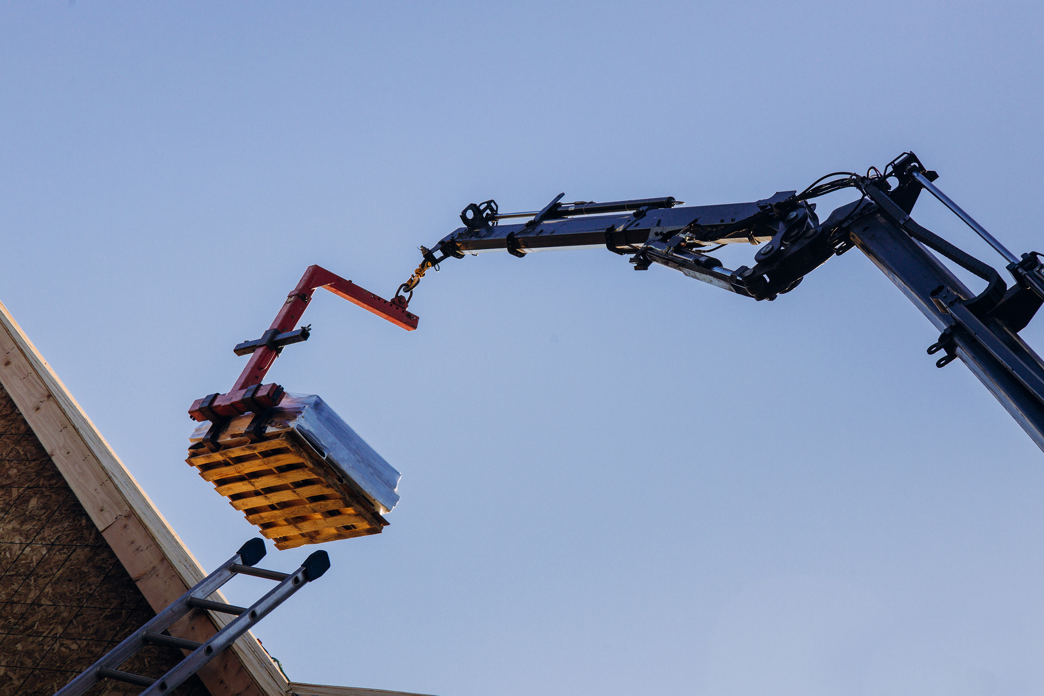 Crane lifting materials roofing construction at work.