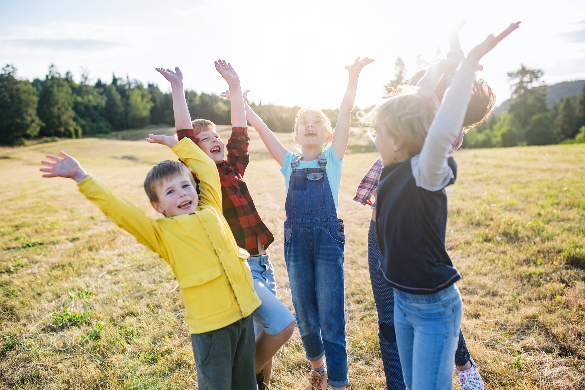Group of school children standing on field trip in nature, playing.