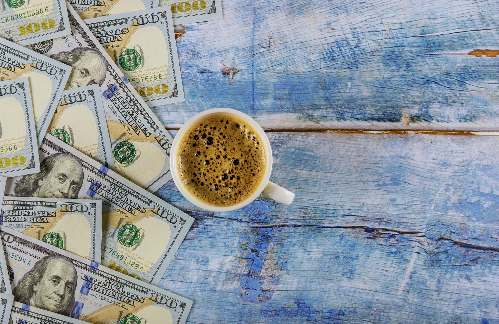 US dollar banknotes american dollars and cup of black coffee on rustic table, top view.