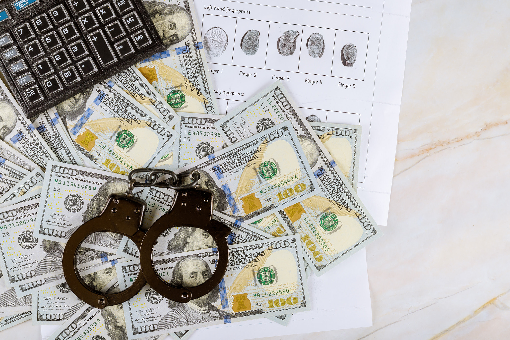 Handcuffs a criminal, fingerprints on a calculator on US dollar banknotes