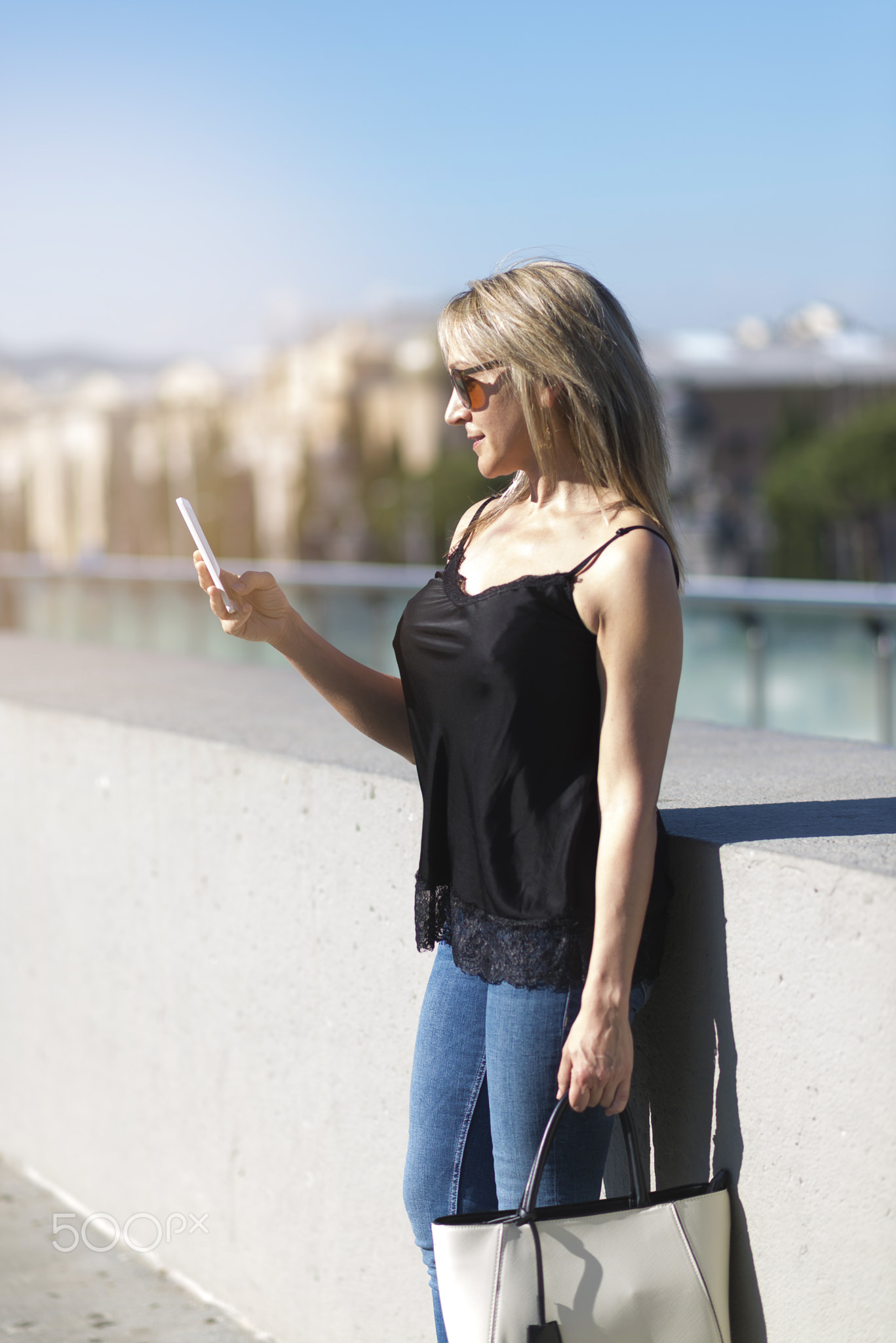 Side view of a girl checking a smart phone on the street