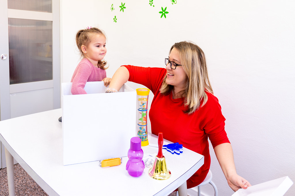 Toddler girl in child occupational therapy session doing sensory playful exercises with her therapis by Andrea Obzerova on 500px.com