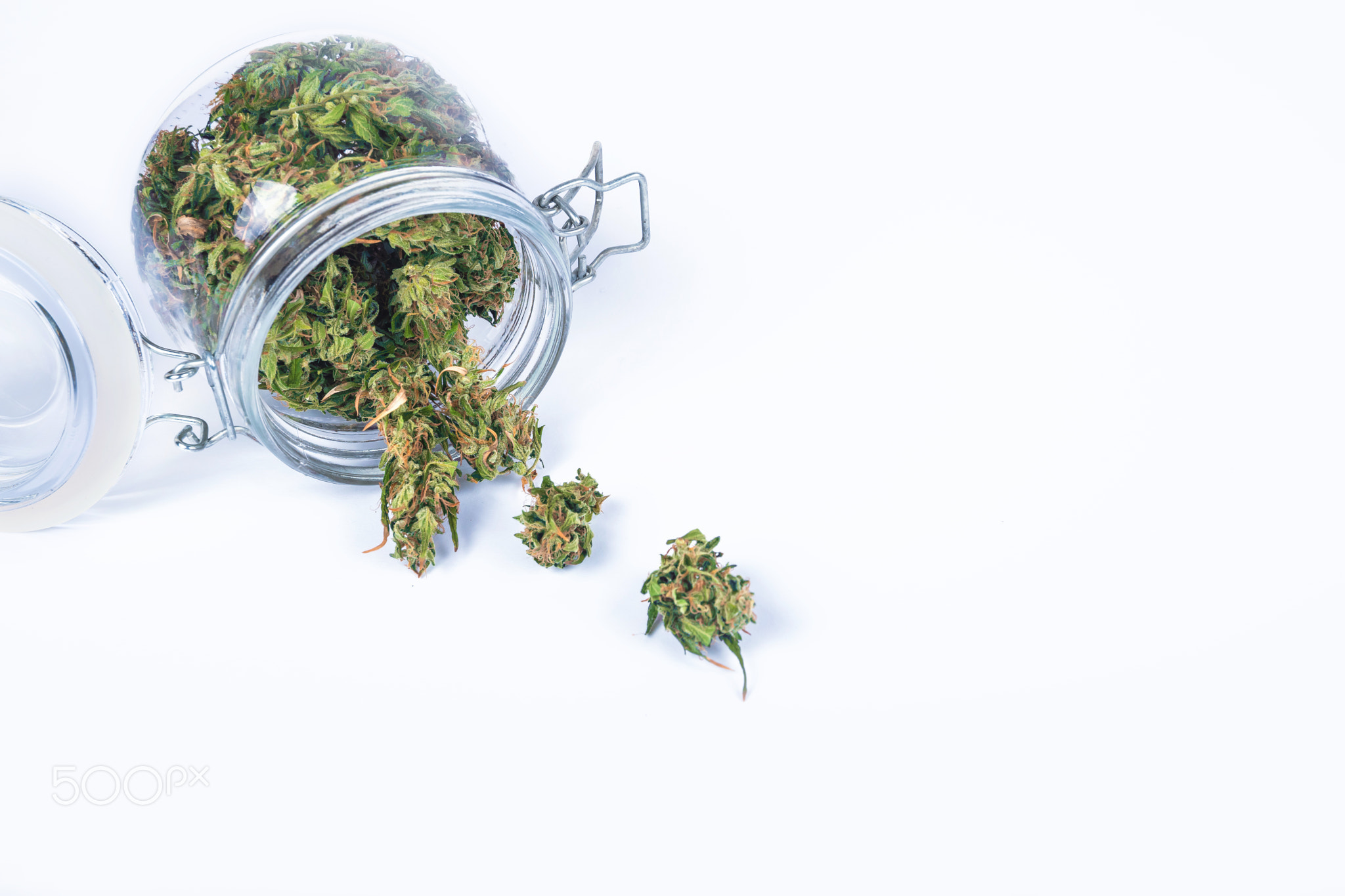 Fresh green buds or flowers of cannabis marijuana weed in opened transparent glass jar isolated on w