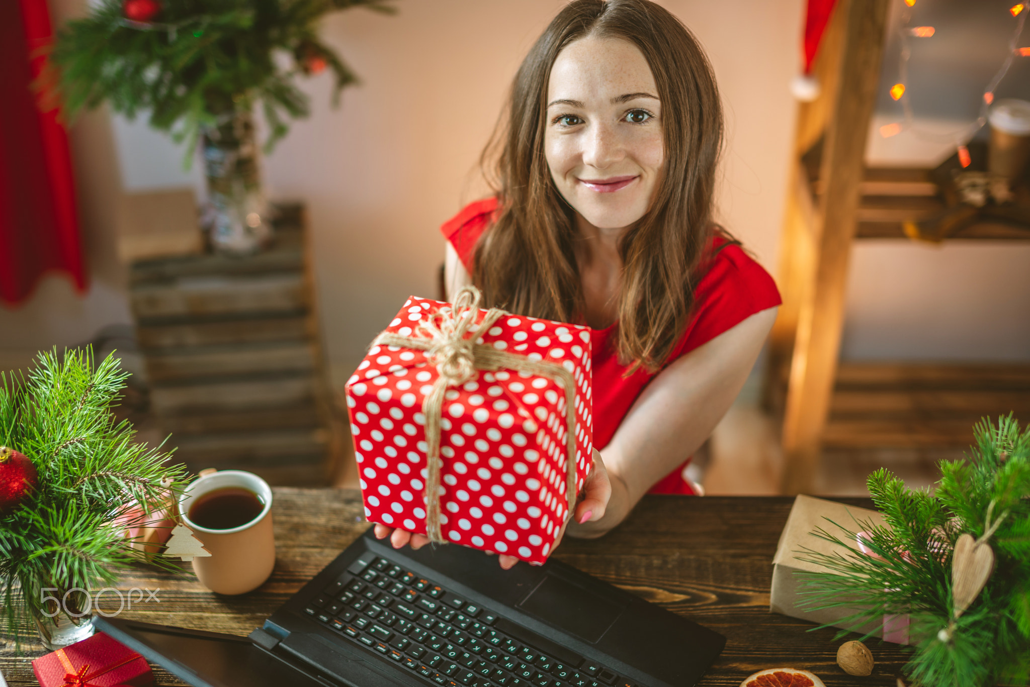 Beautiful woman in a red dress receives a gift via the Internet for the New year. Online shopping fo