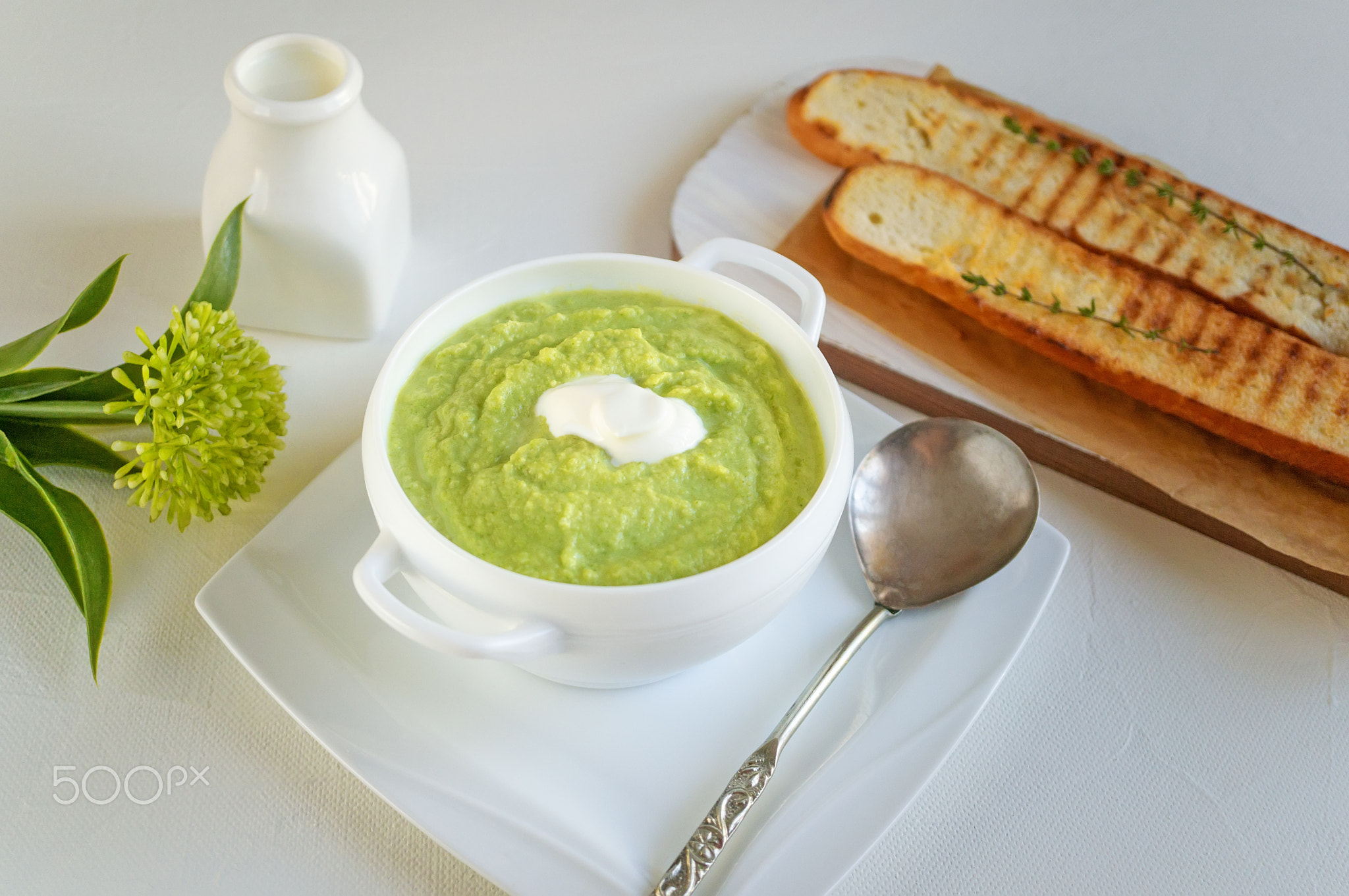 a bowl with vegetables puree on a white background. large white bowl with vegetable green cream soup