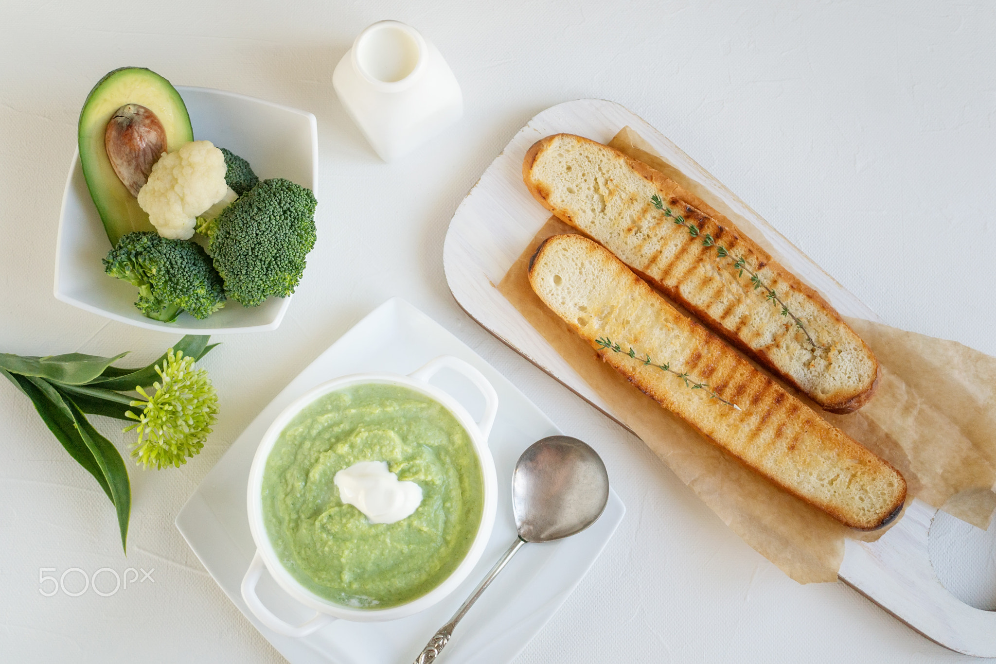 a bowl with vegetables puree on a white background. large white bowl with vegetable green cream soup