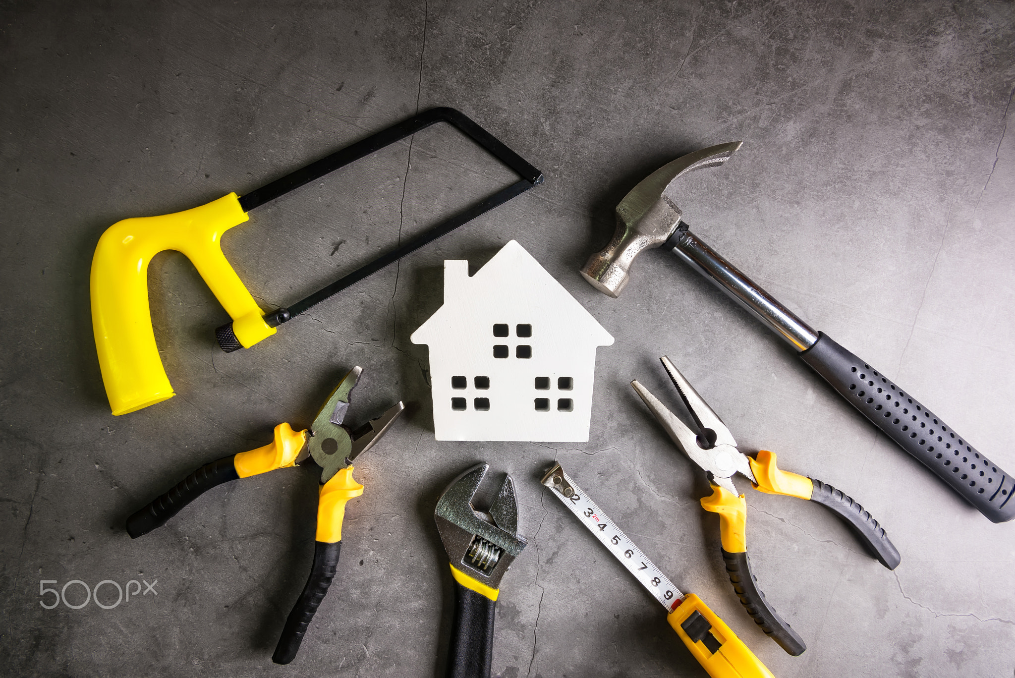 Wooden house and construction tools on stone pattern background