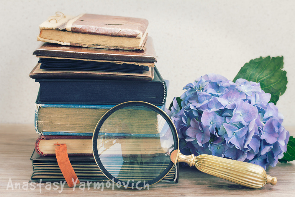 old books with flowers and looking glass