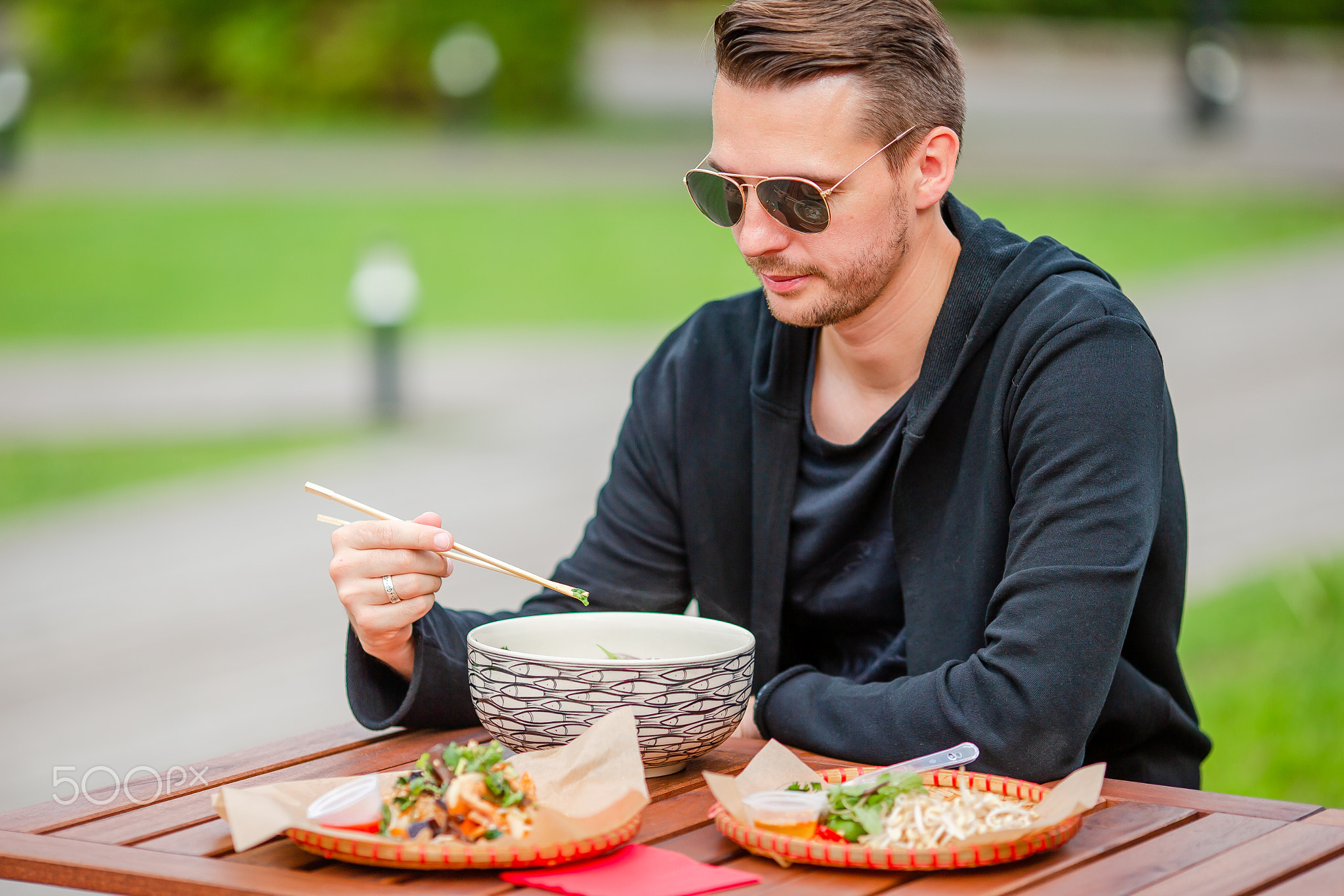 Young man eating take away noodles on the street