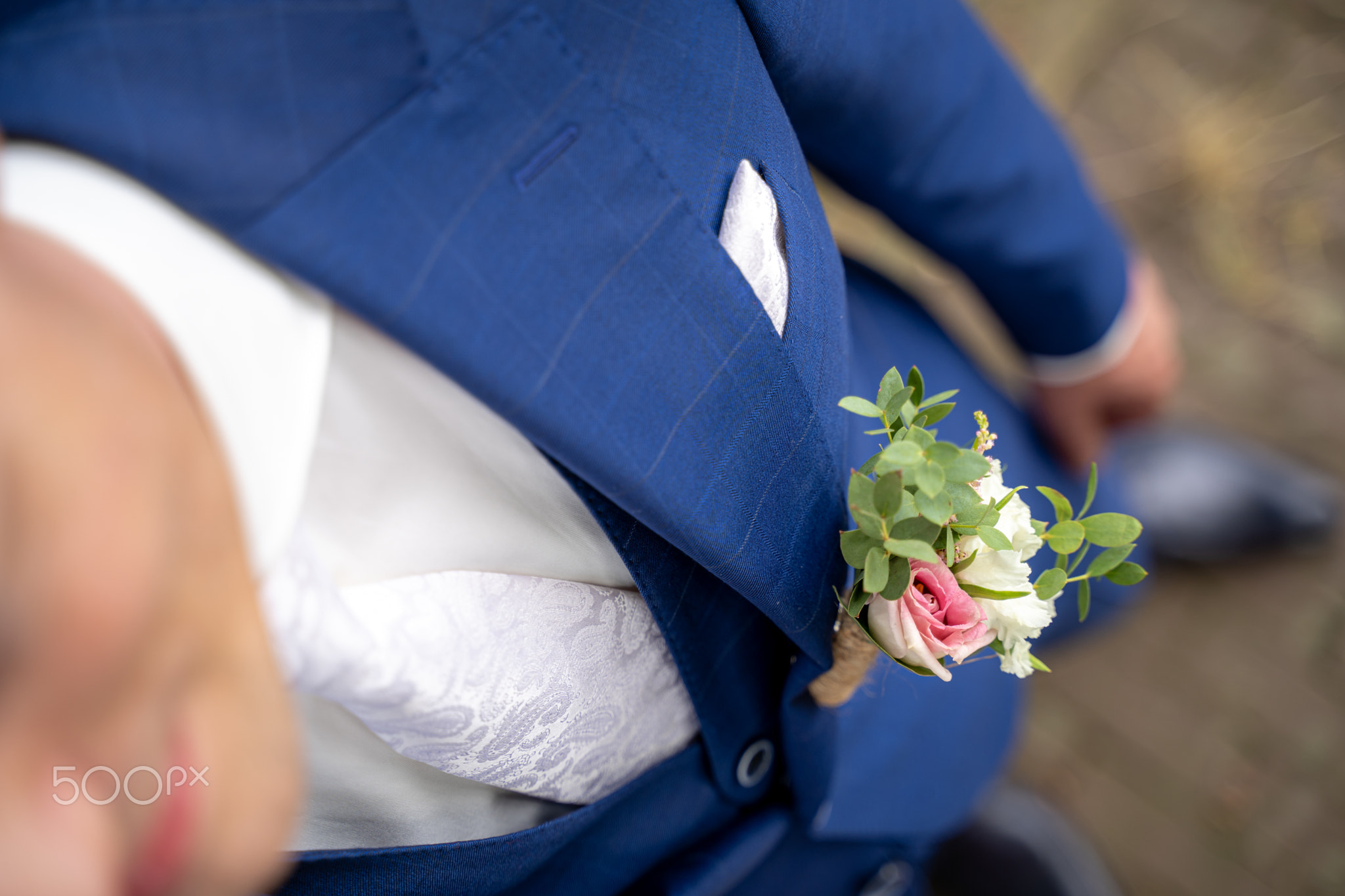 Happy and young groom with colorful coursage on a bleu jacket