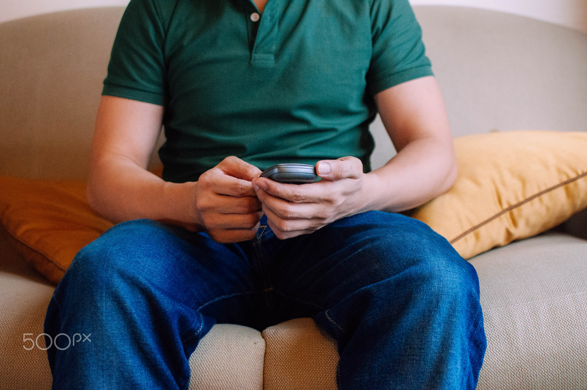 A young male adult is using a device to measure blood sugar while sitting on a couch