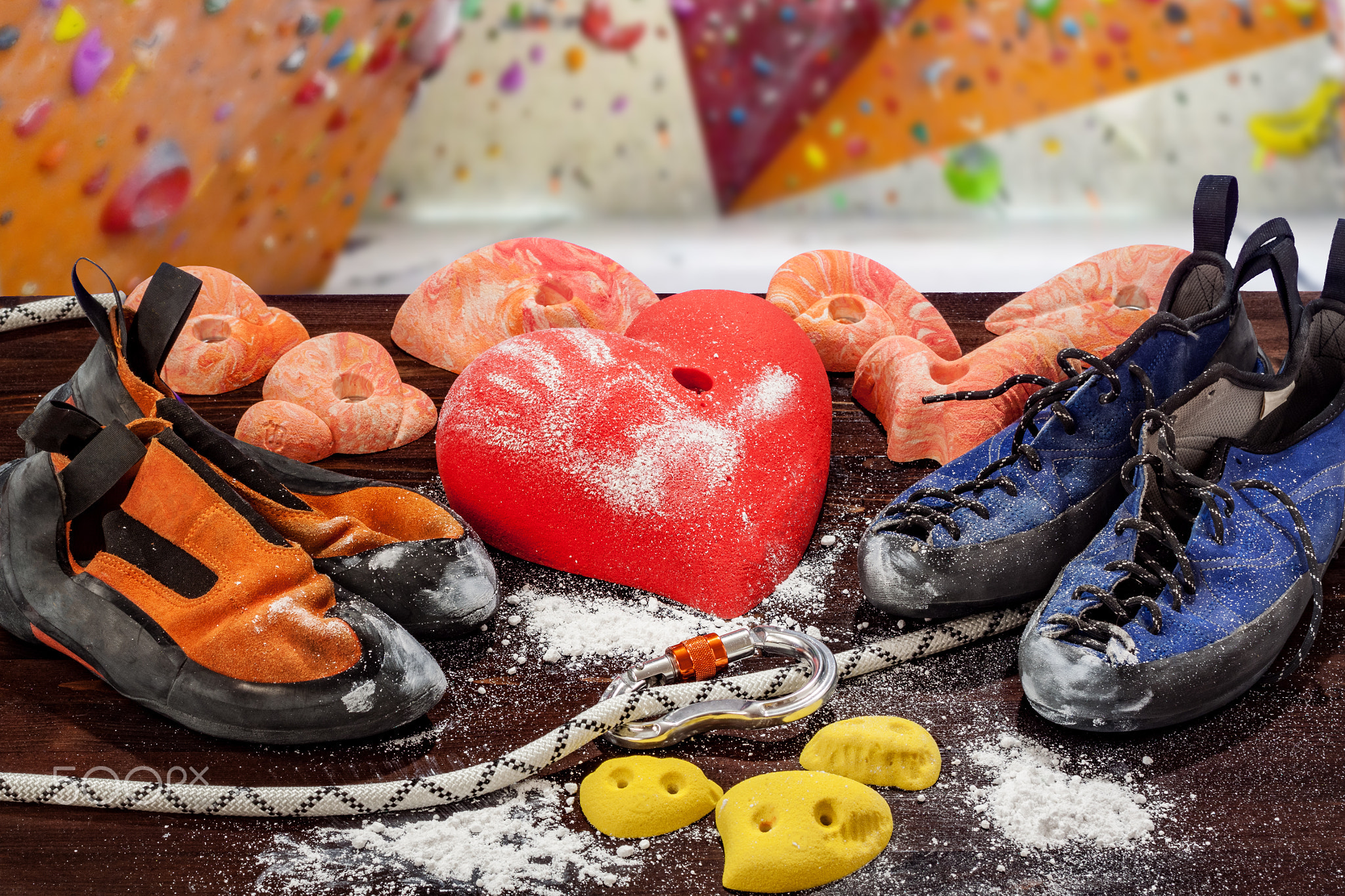 Two pairs of climbing shoes lie next to the climbing hook in the form of a heart. In the foreground,