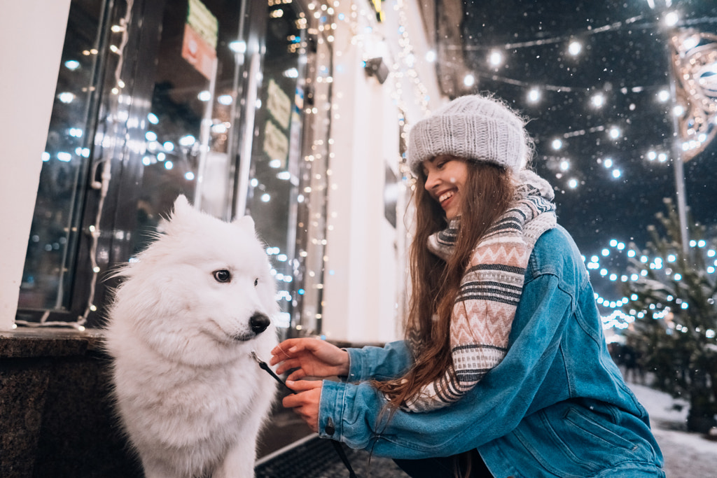 A young woman crouched beside a dog on a winter street. by Oleksii Hrecheniuk on 500px.com