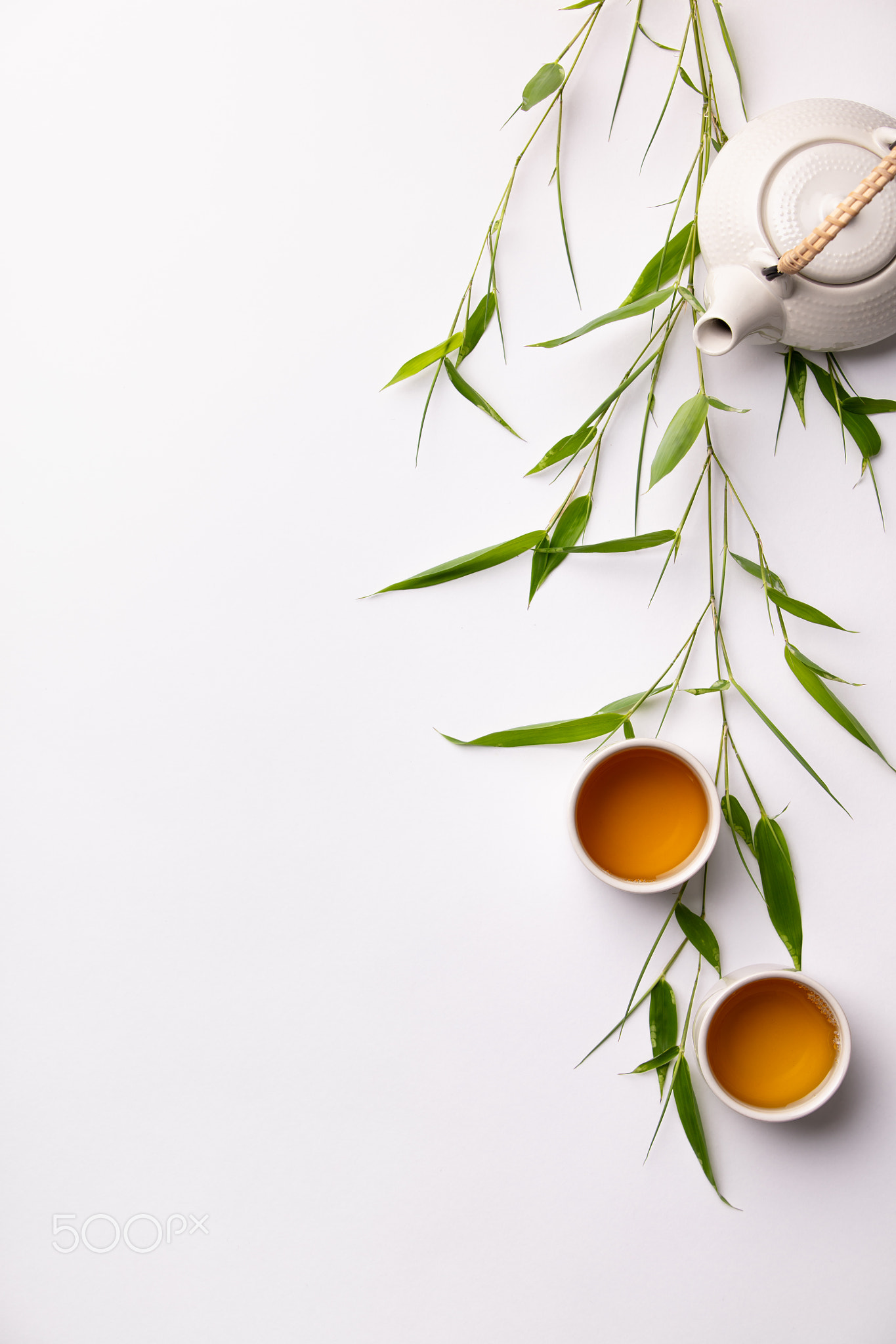 Asian food background set with green tea, cups and teapot with bamboo branches