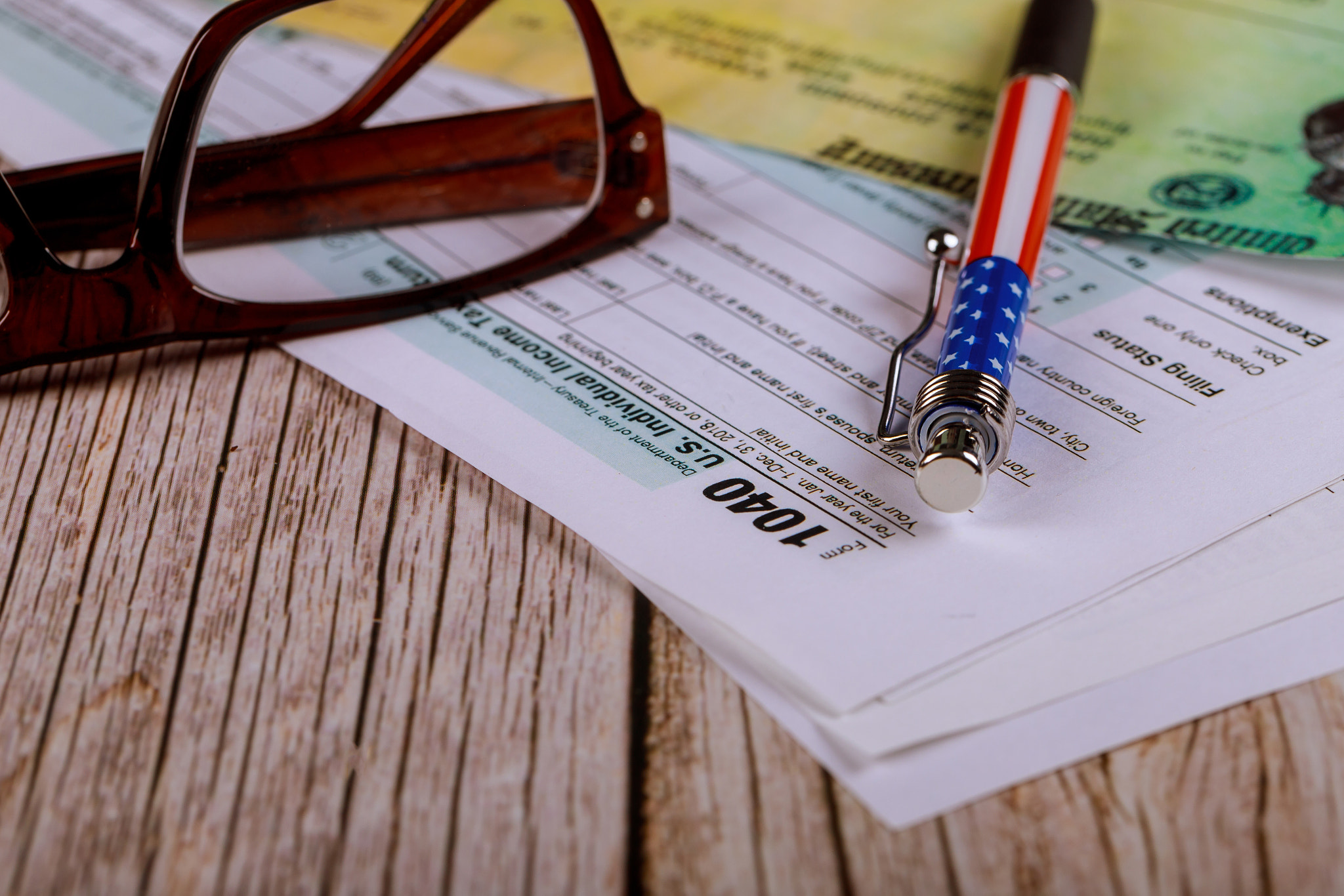 Tax 1040 forms with pen with U.S. individual income tax and glasses