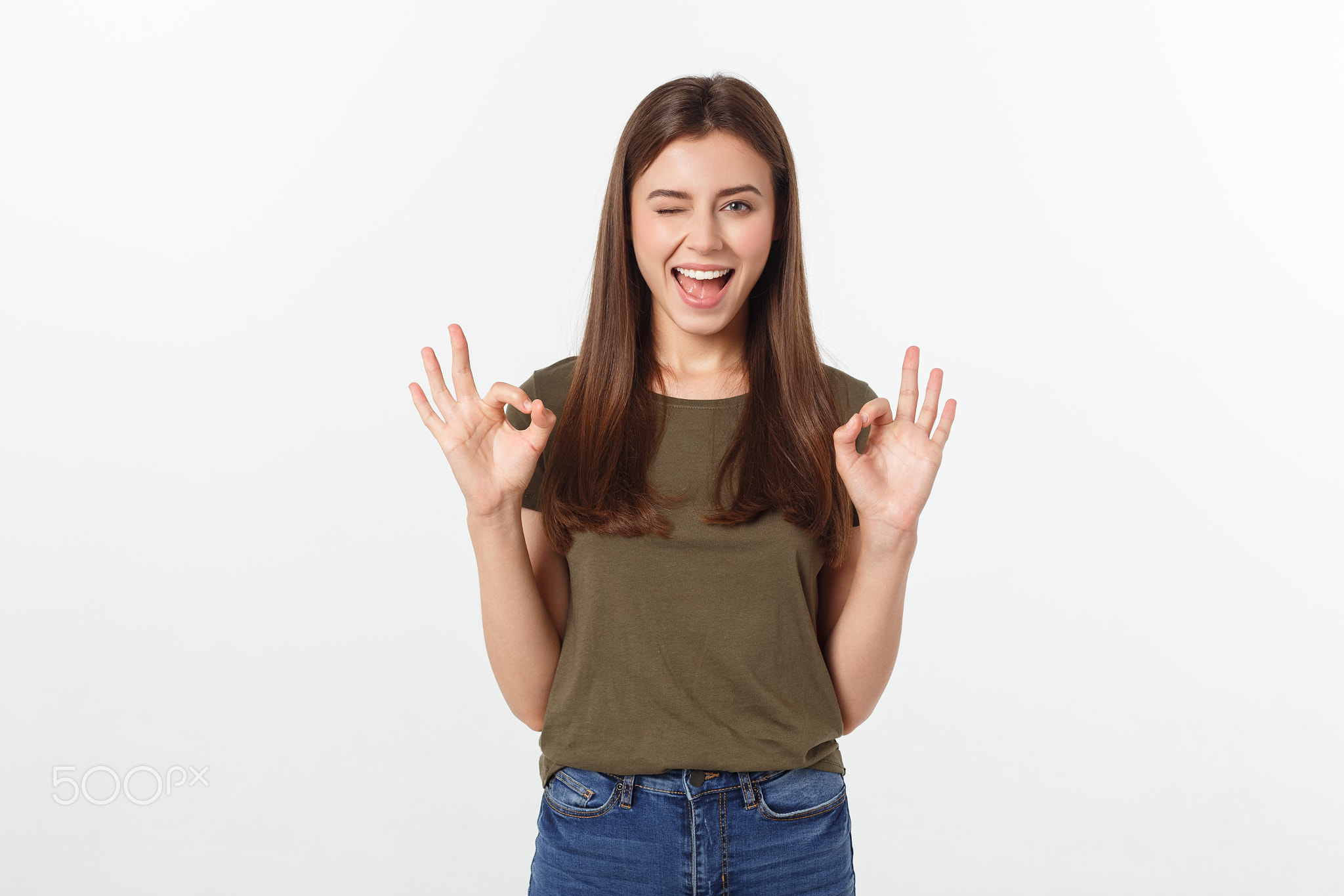 Happy young woman showing ok sign with fingers an winking isolated on a gray background.