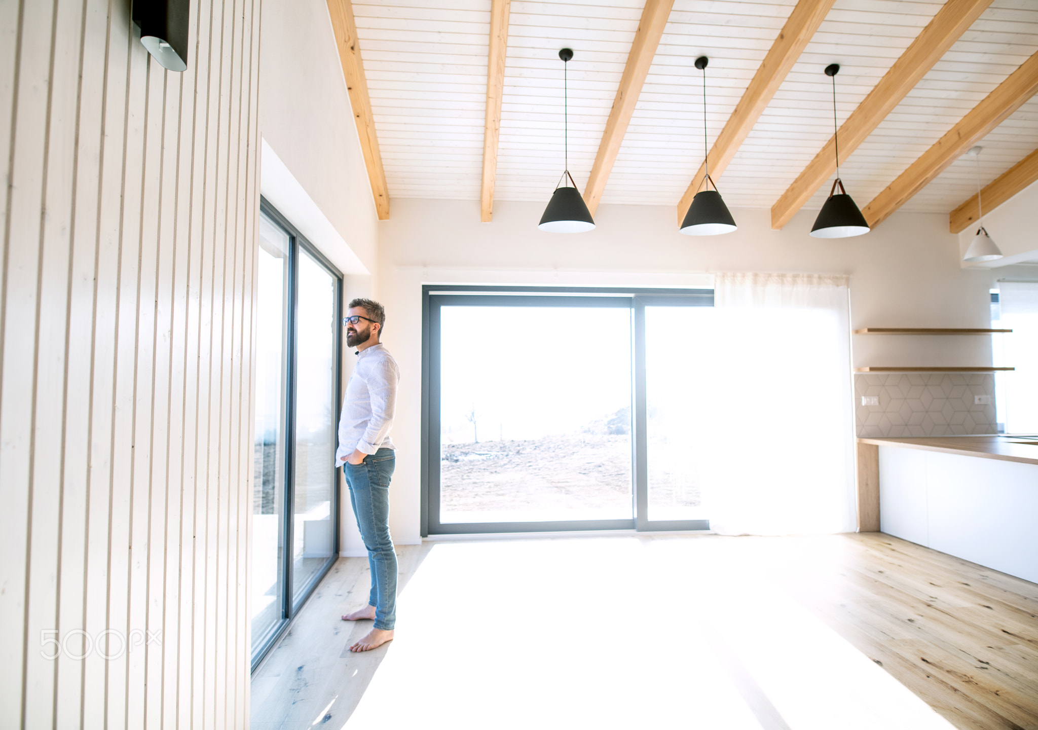 Mature man standing in unfurnished house, moving in new home concept.