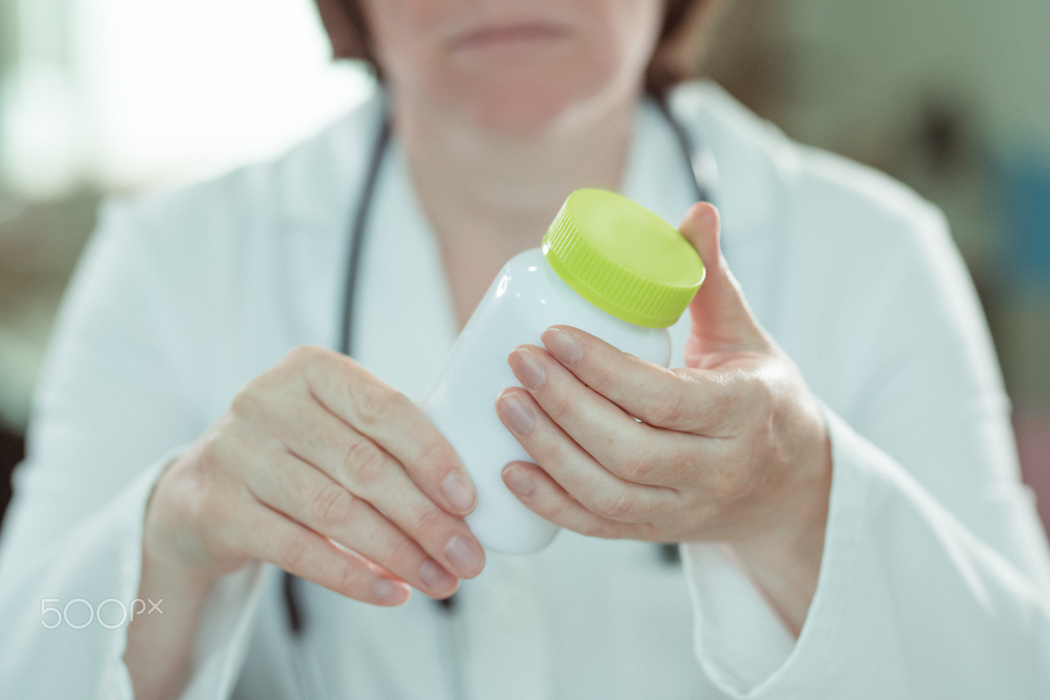Female doctor holding bottle of dietary supplement