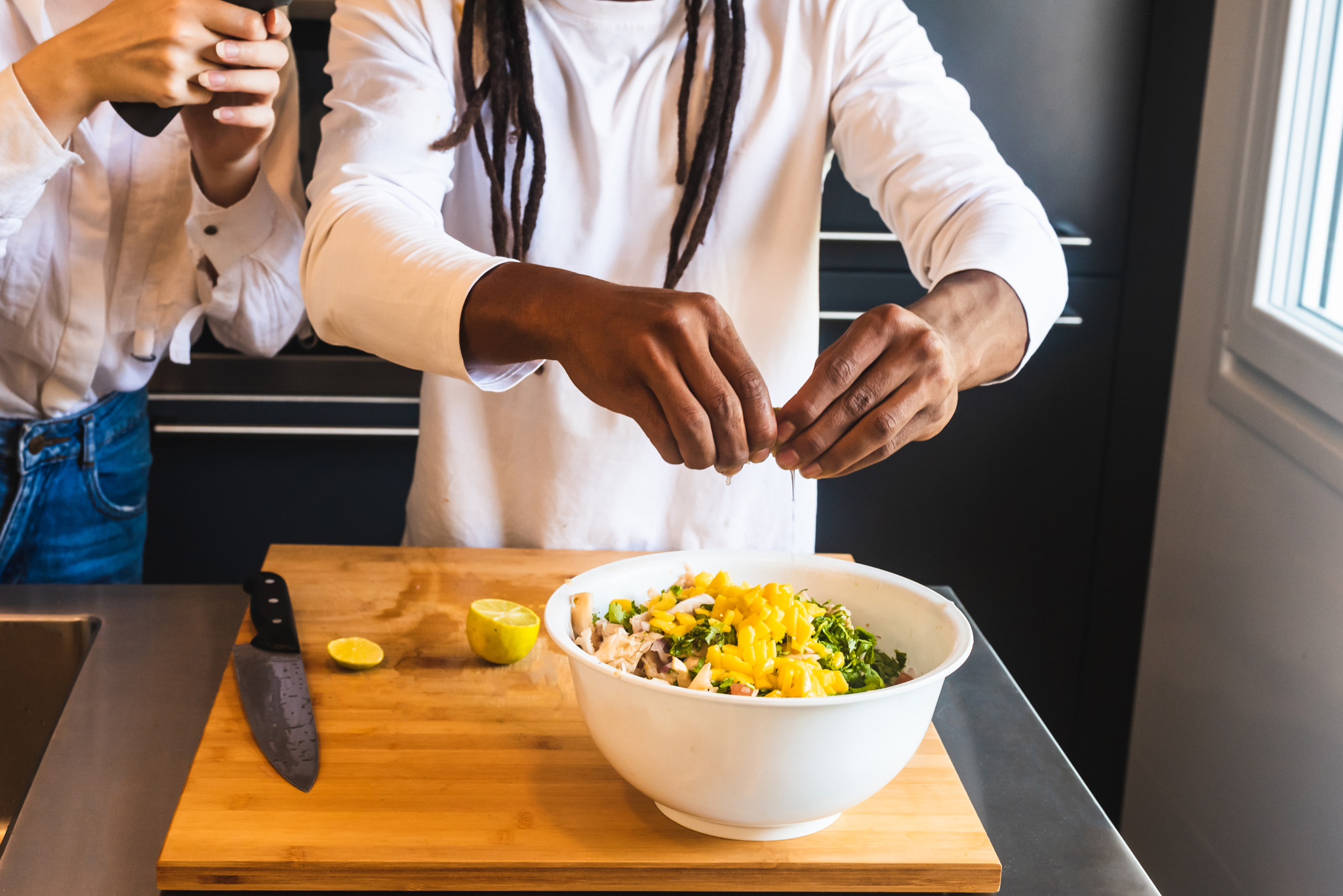 Black guy putting lemon to a salad