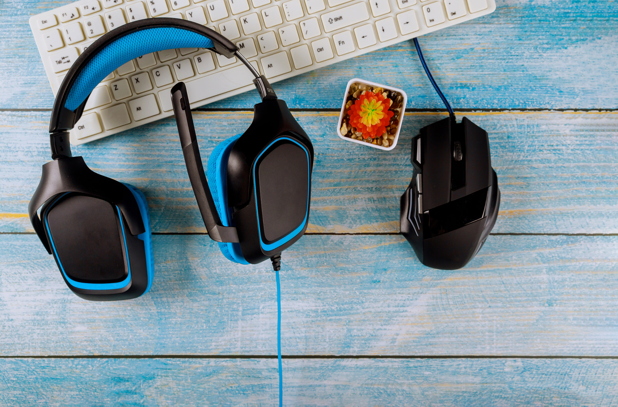 Gamepads headphones and keyboard with mouse on old wood blue table