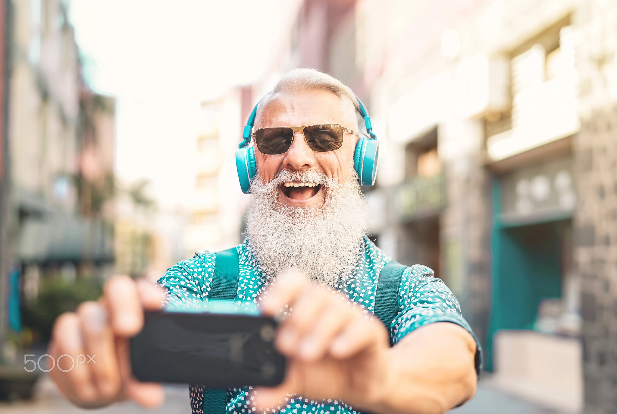 Senior bearded man taking selfie with mobile phone
