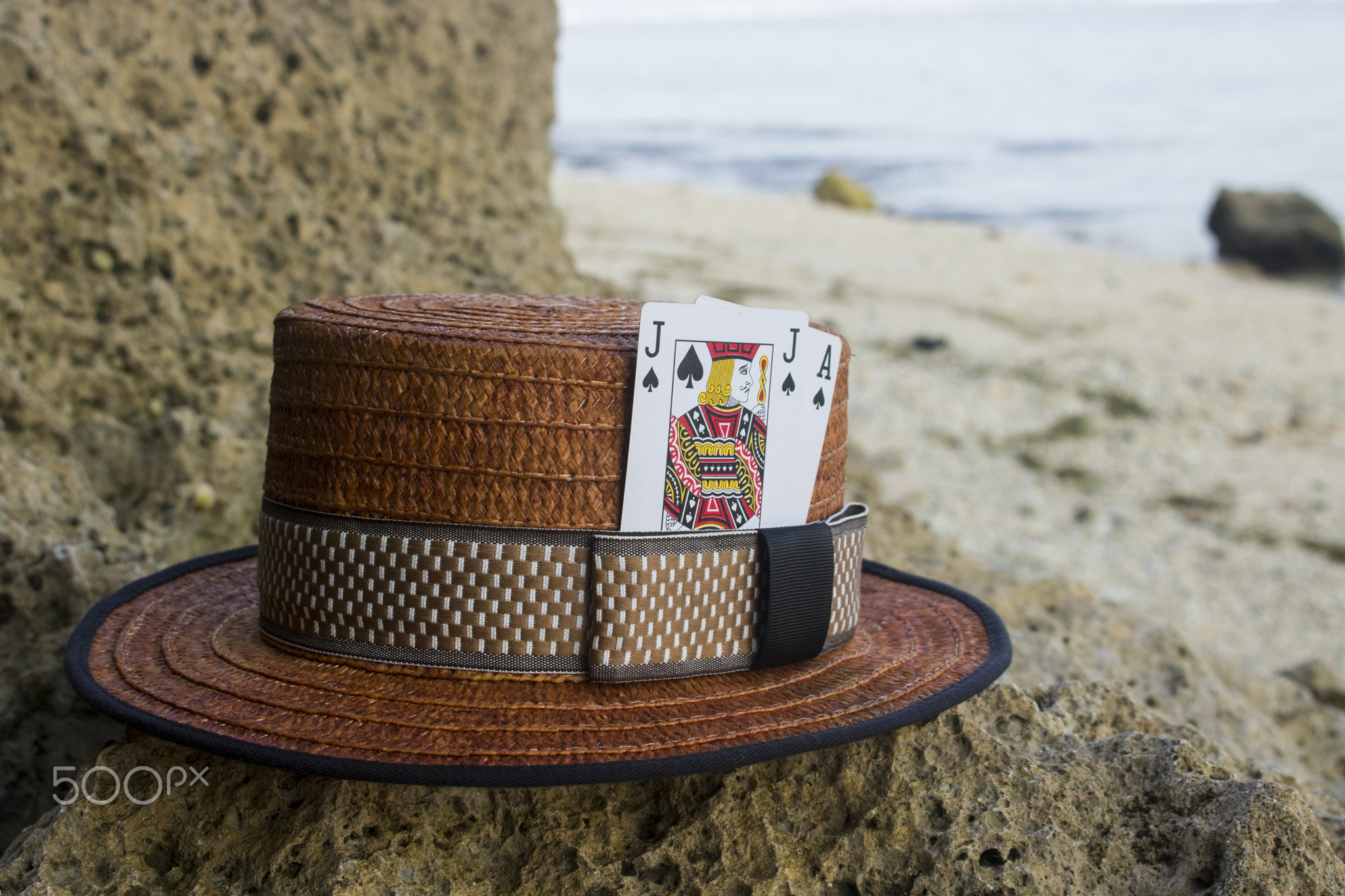 brown boater hat with black jack card on beach