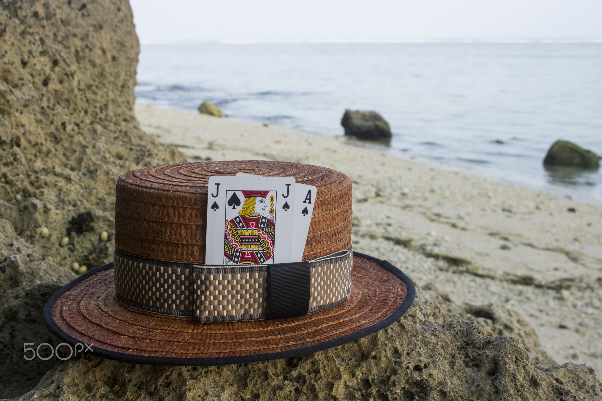 brown boater hat with black jack card on beach