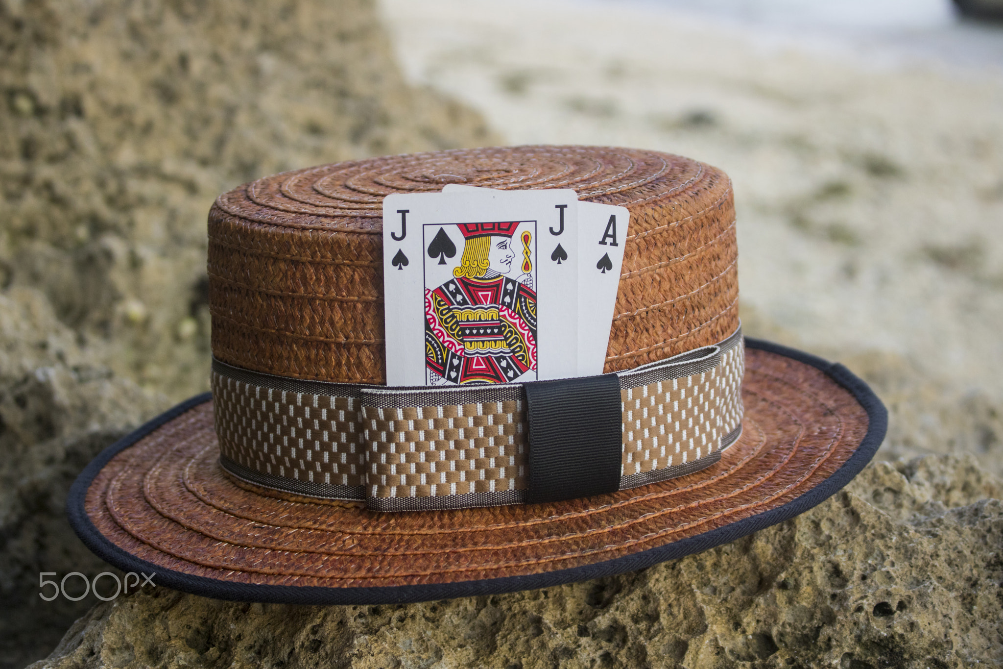 brown boater hat with black jack card on beach