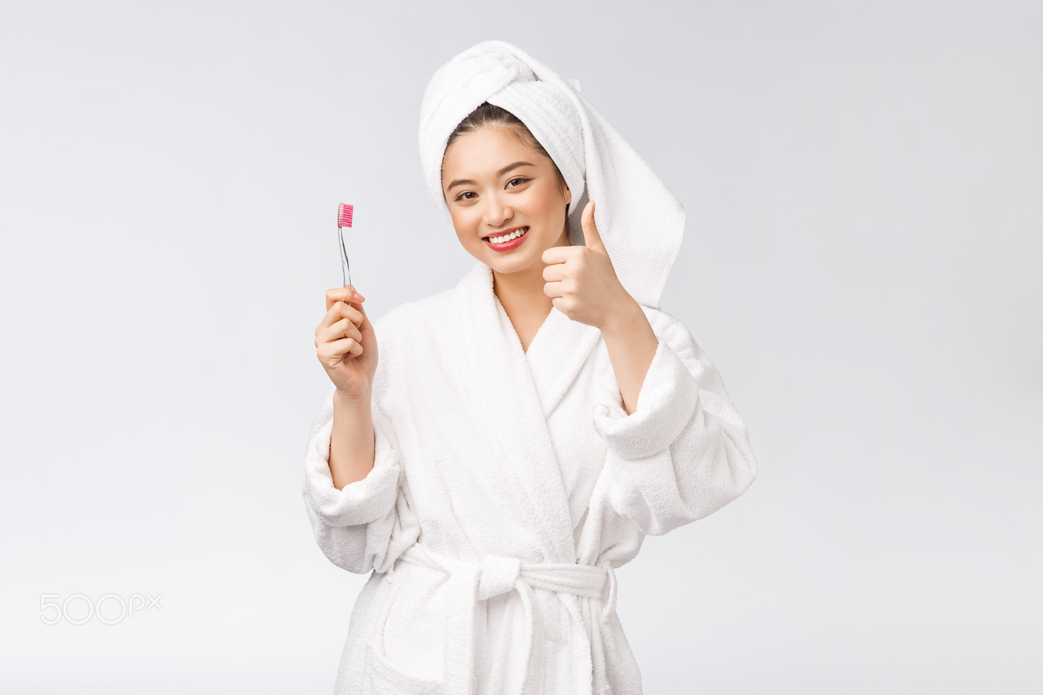 Asian happy woman with toothbrush in bathrobe morning mood
