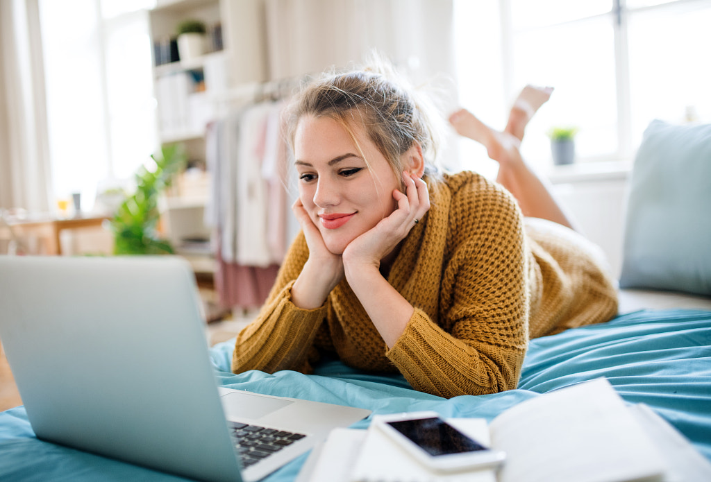 Young woman with laptop lying on bed indoors at home, relaxing. by Jozef Polc on 500px.com