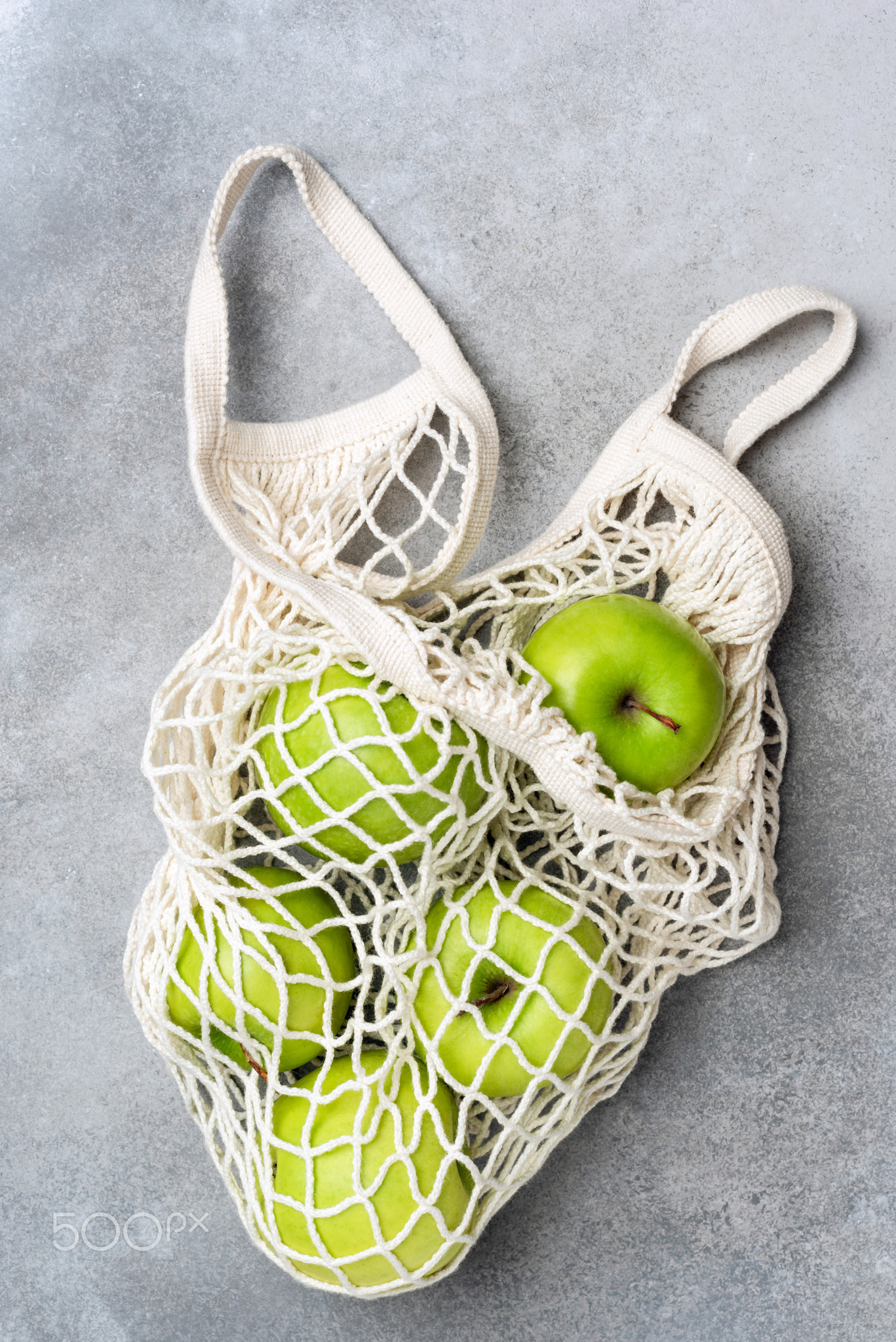 Mesh shopping bag with green apples