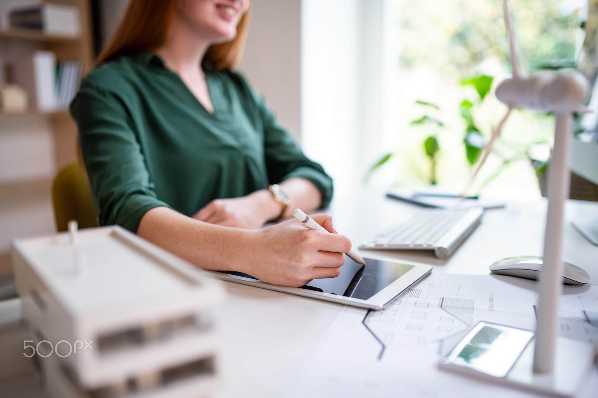 Midsection of young architect sitting at the desk indoors in office