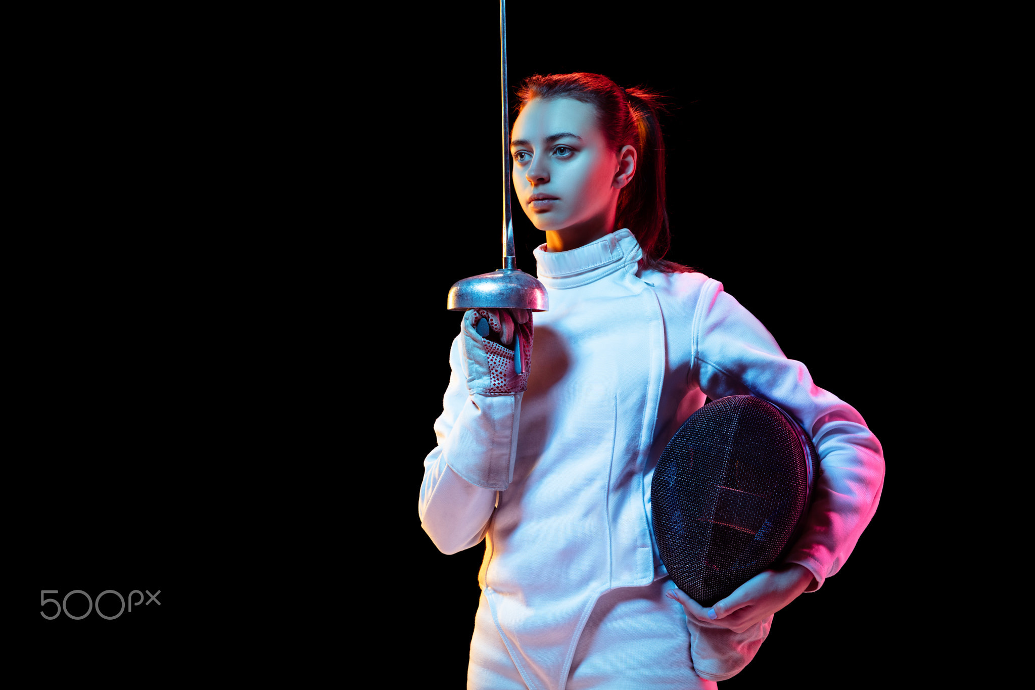 Teen girl in fencing costume with sword in hand isolated on black