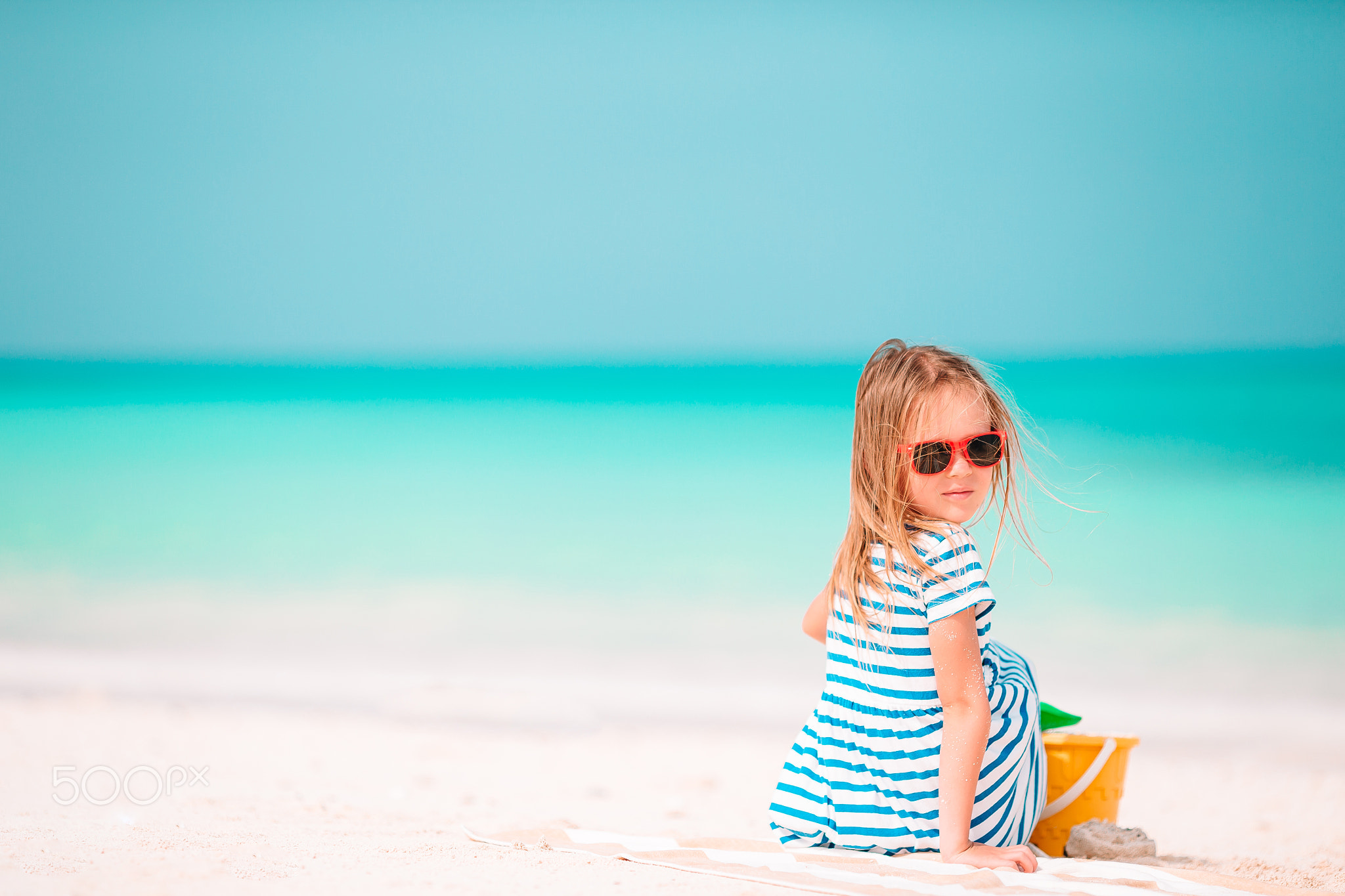 Little adorable girl playing on beach with ball