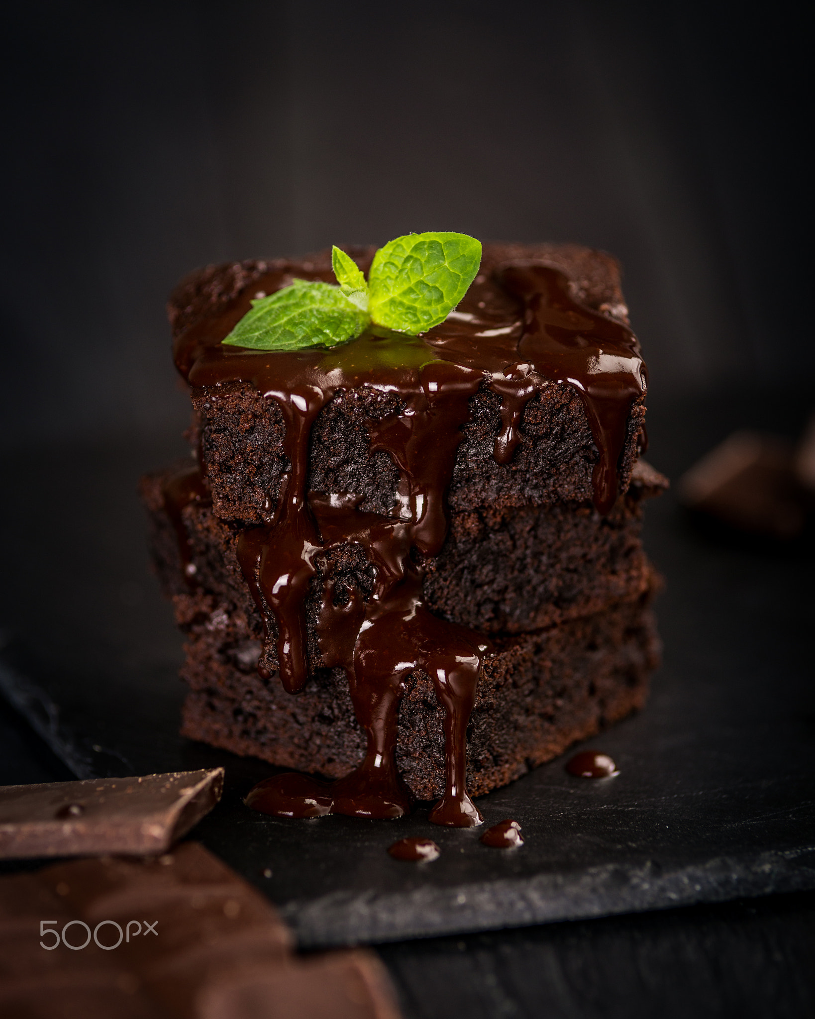 A stack of chocolate brownies on wooden background with mint leaf