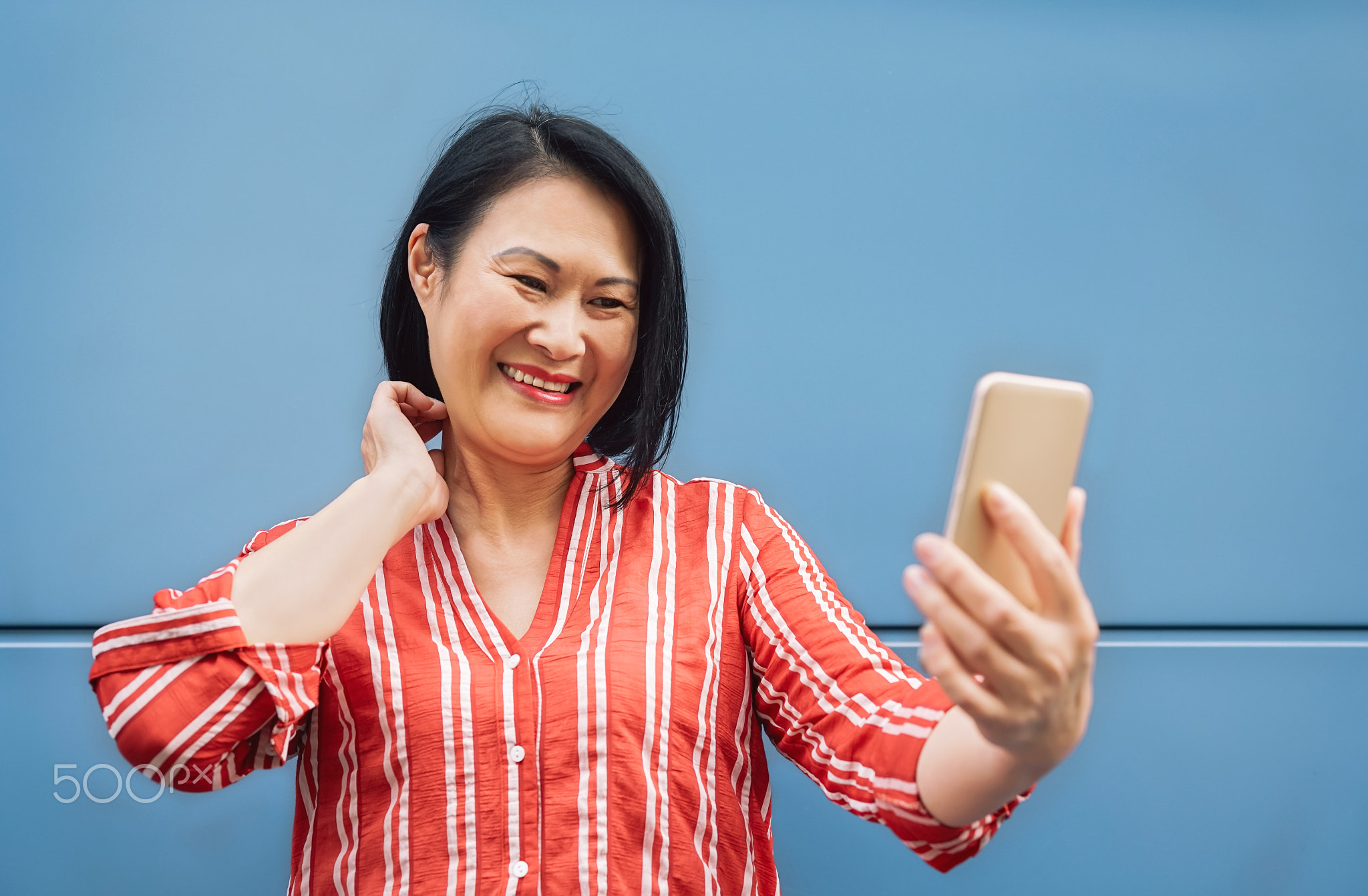 Happy Asian woman using mobile smartphone outdoor